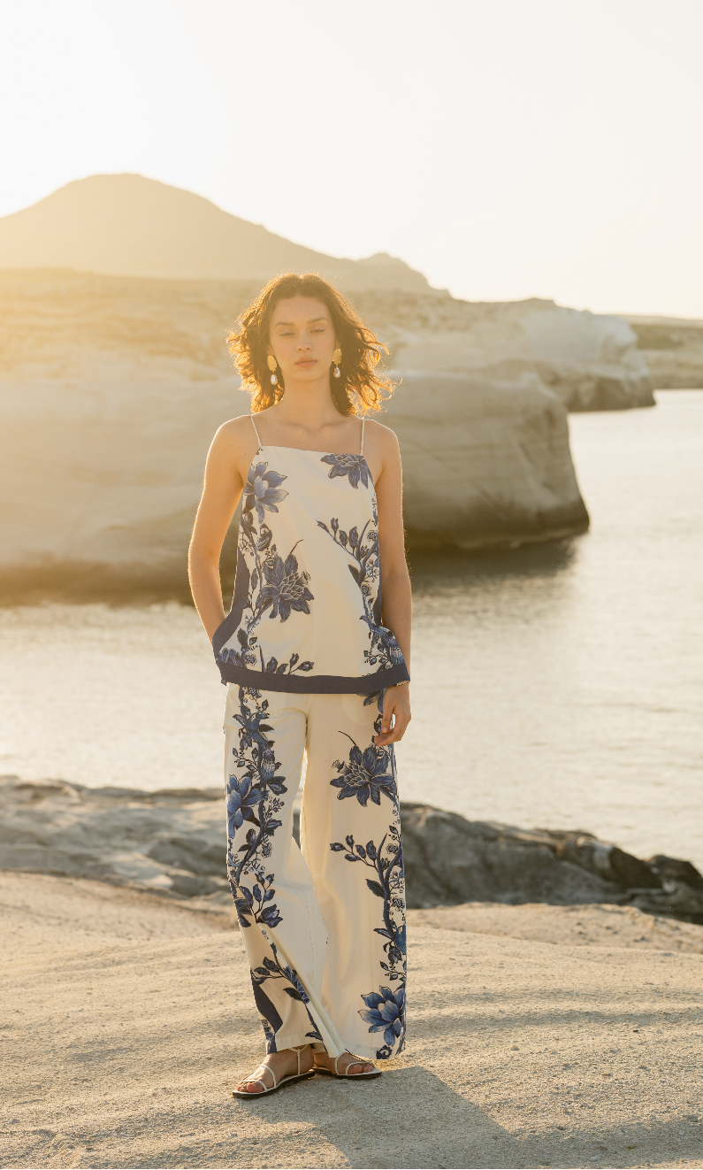 Woman in a floral matching set standing on a beach with rocks and water in the background Calling June