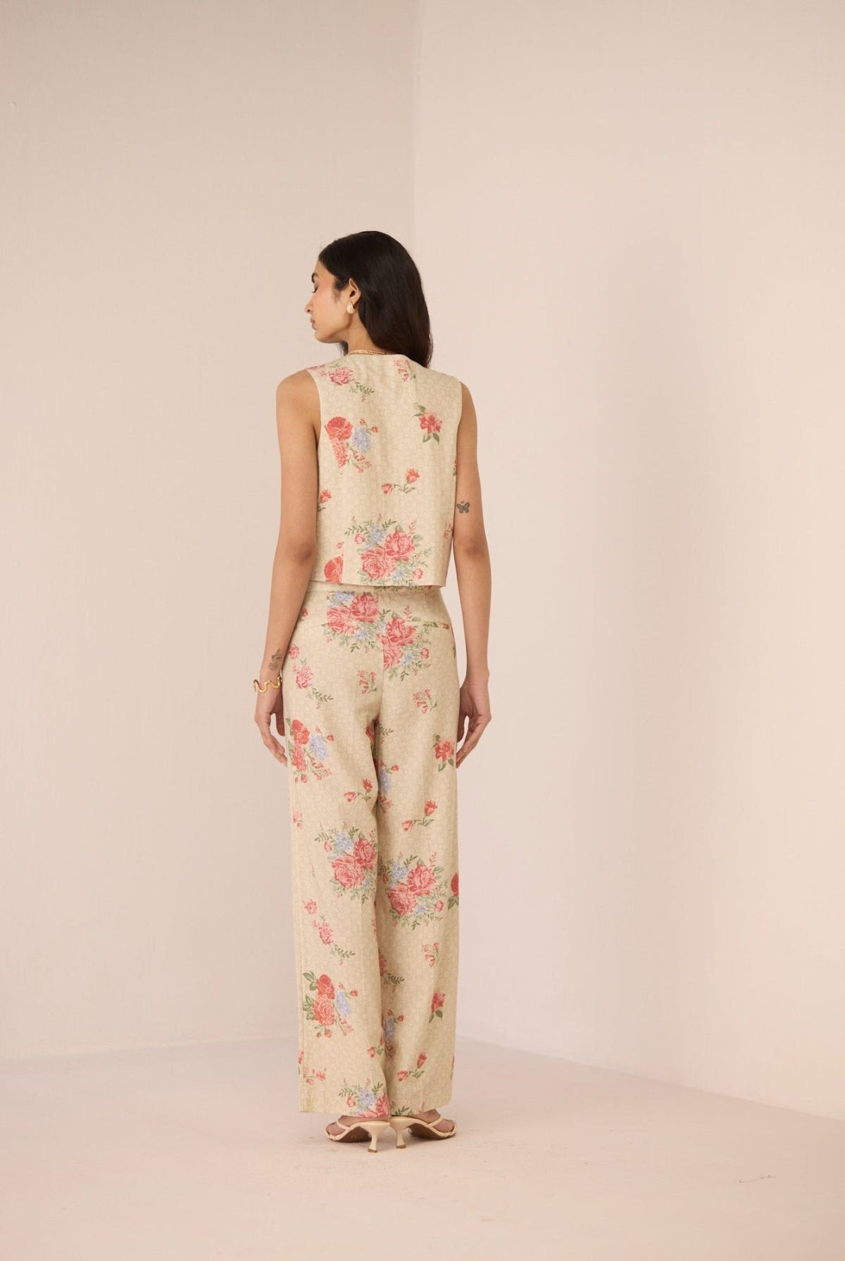 Woman wearing a floral sleeveless top and pants on a beige background Calling June