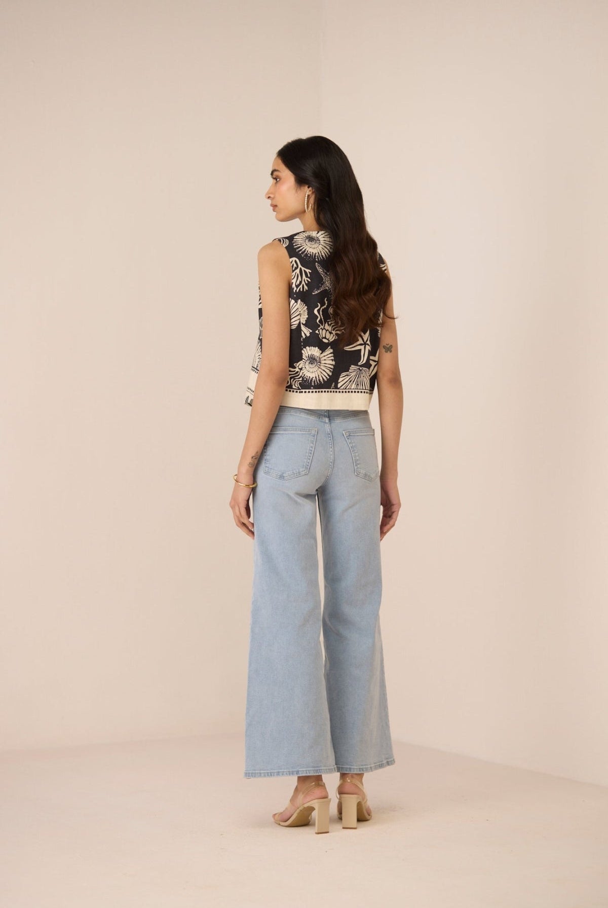 Woman wearing a floral top and light blue jeans on a beige background Calling June