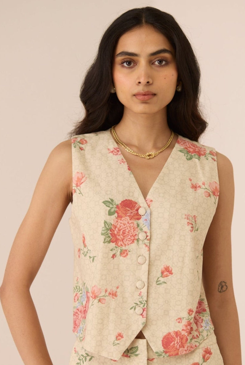 Woman wearing a floral sleeveless top and pants against a plain background Calling June