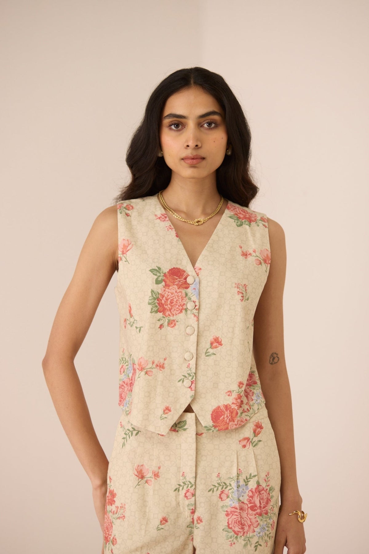 Woman wearing a floral sleeveless top and pants against a plain background Calling June