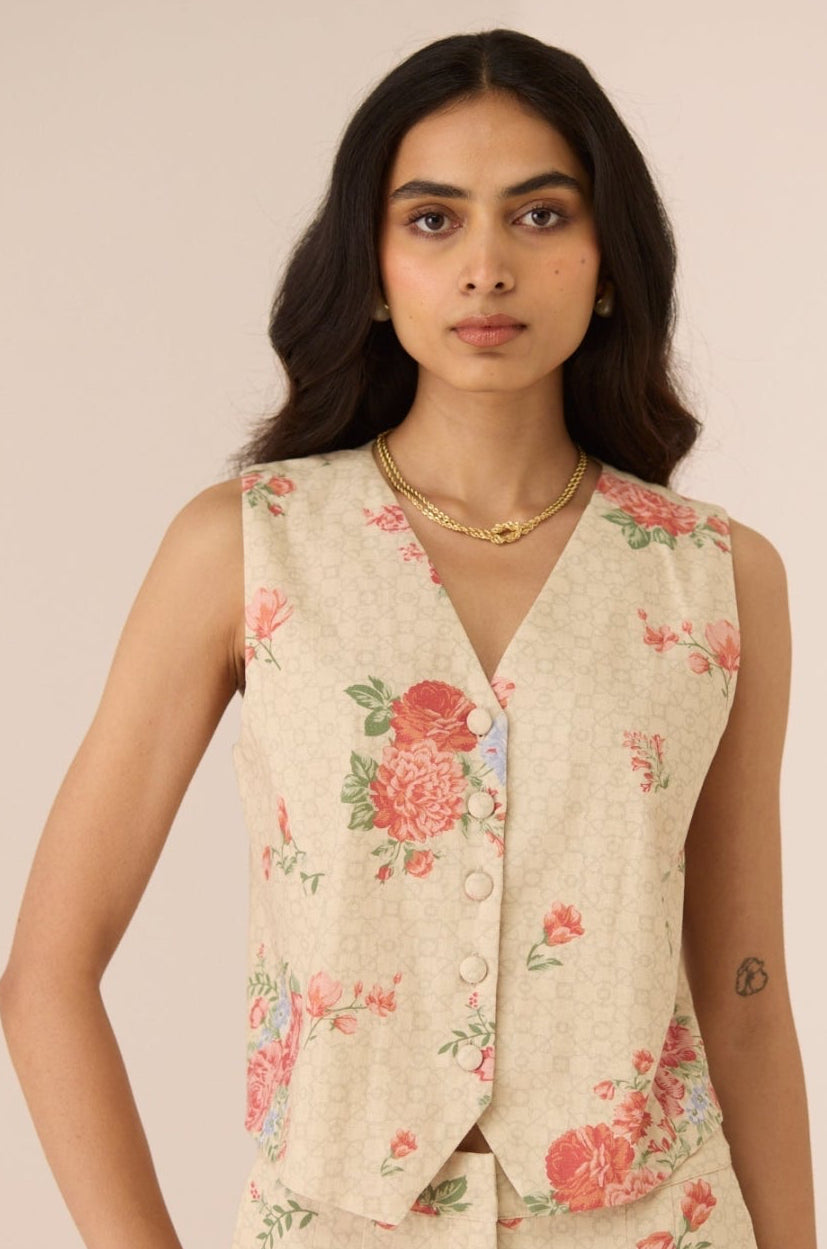 Woman wearing a floral sleeveless top and pants against a plain background Calling June