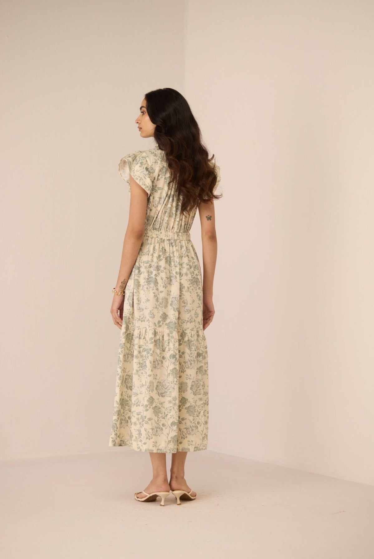 Woman wearing a floral dress against a plain background Calling June