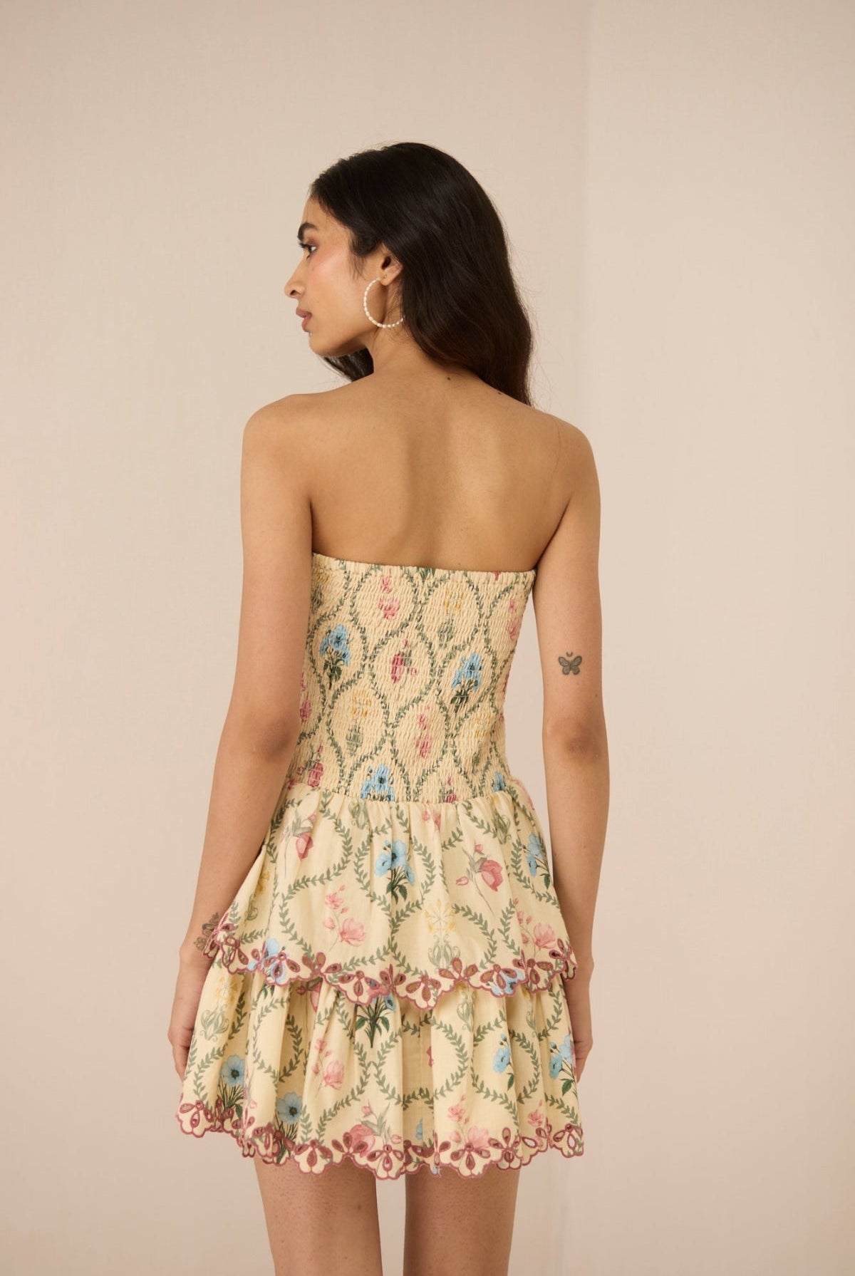 Woman wearing a strapless floral dress against a beige background Calling June