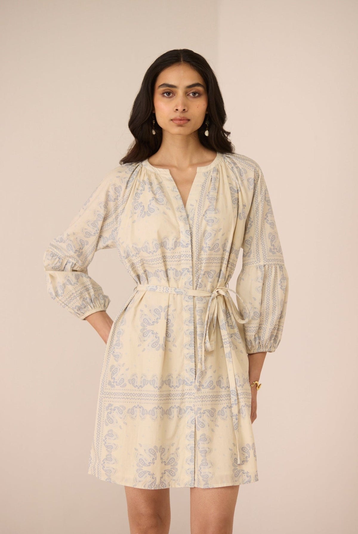 Woman wearing a beige patterned dress against a plain background Calling June