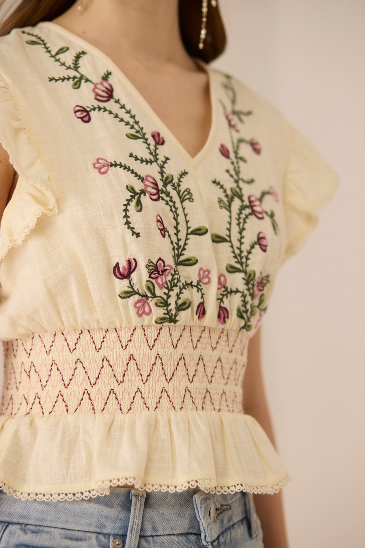 Cream-colored blouse with floral embroidery on a plain background Calling June