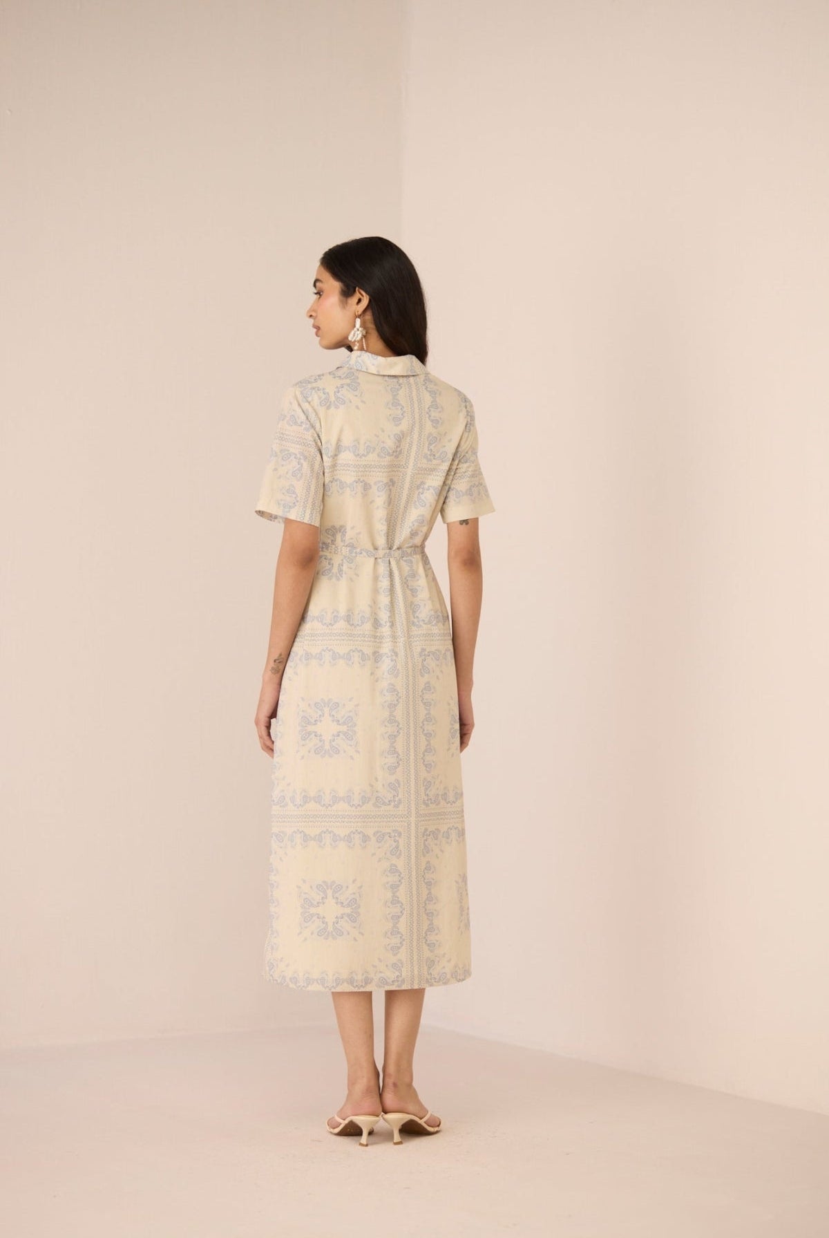 Woman wearing a light-colored dress with a subtle pattern against a plain background Calling June