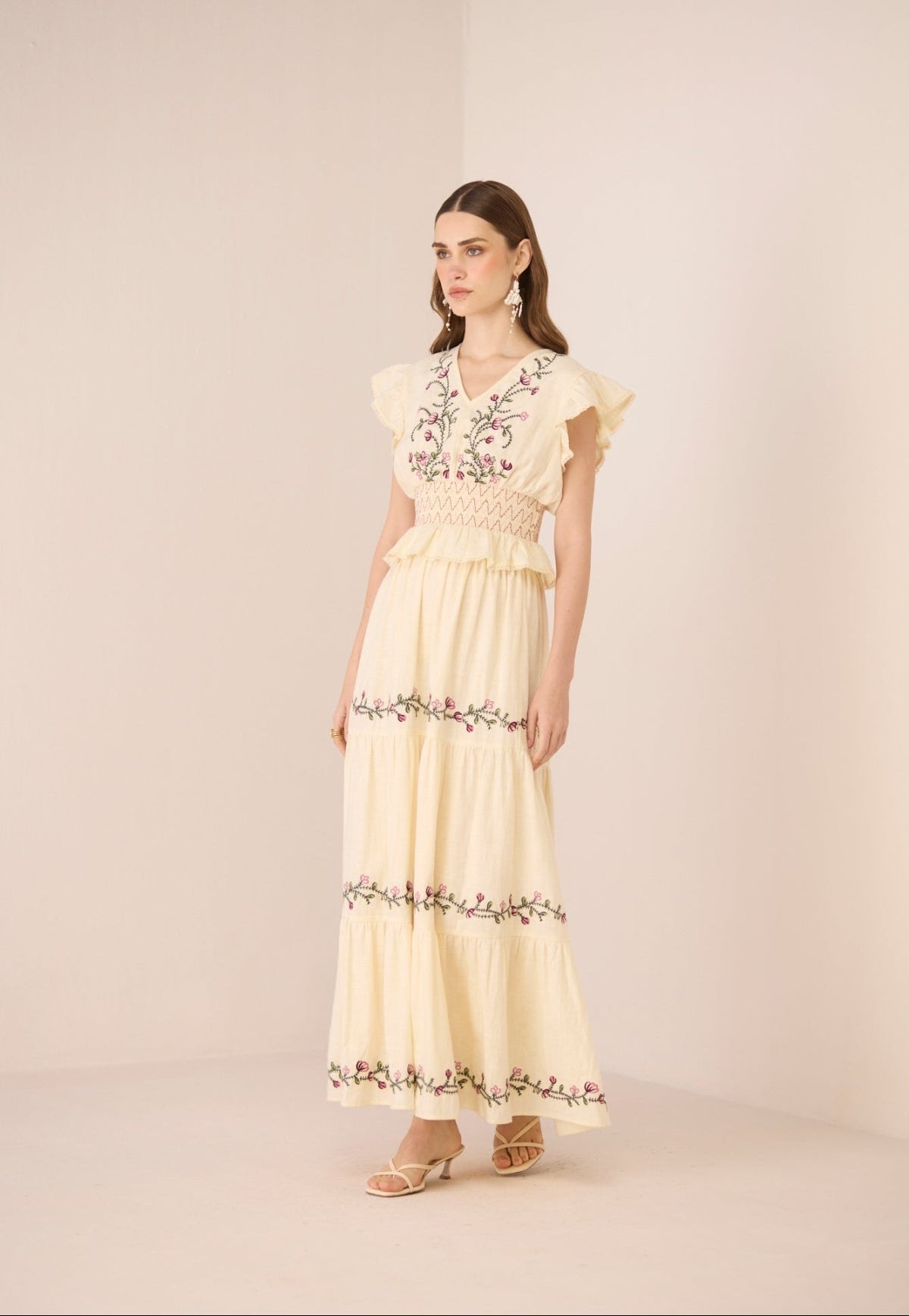 Woman wearing a light yellow set with floral embroidery on a beige background Calling June