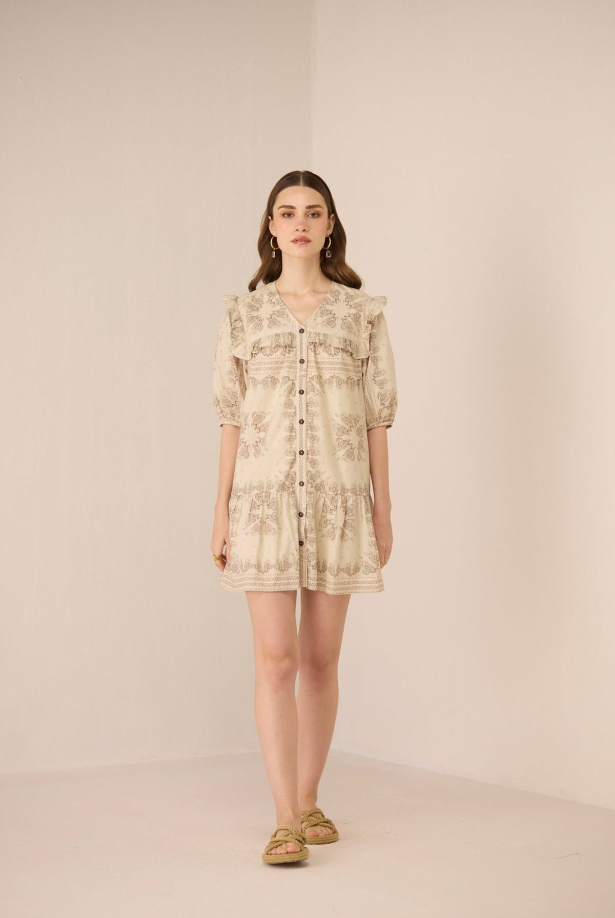 Woman wearing a beige floral dress on a plain background Calling June