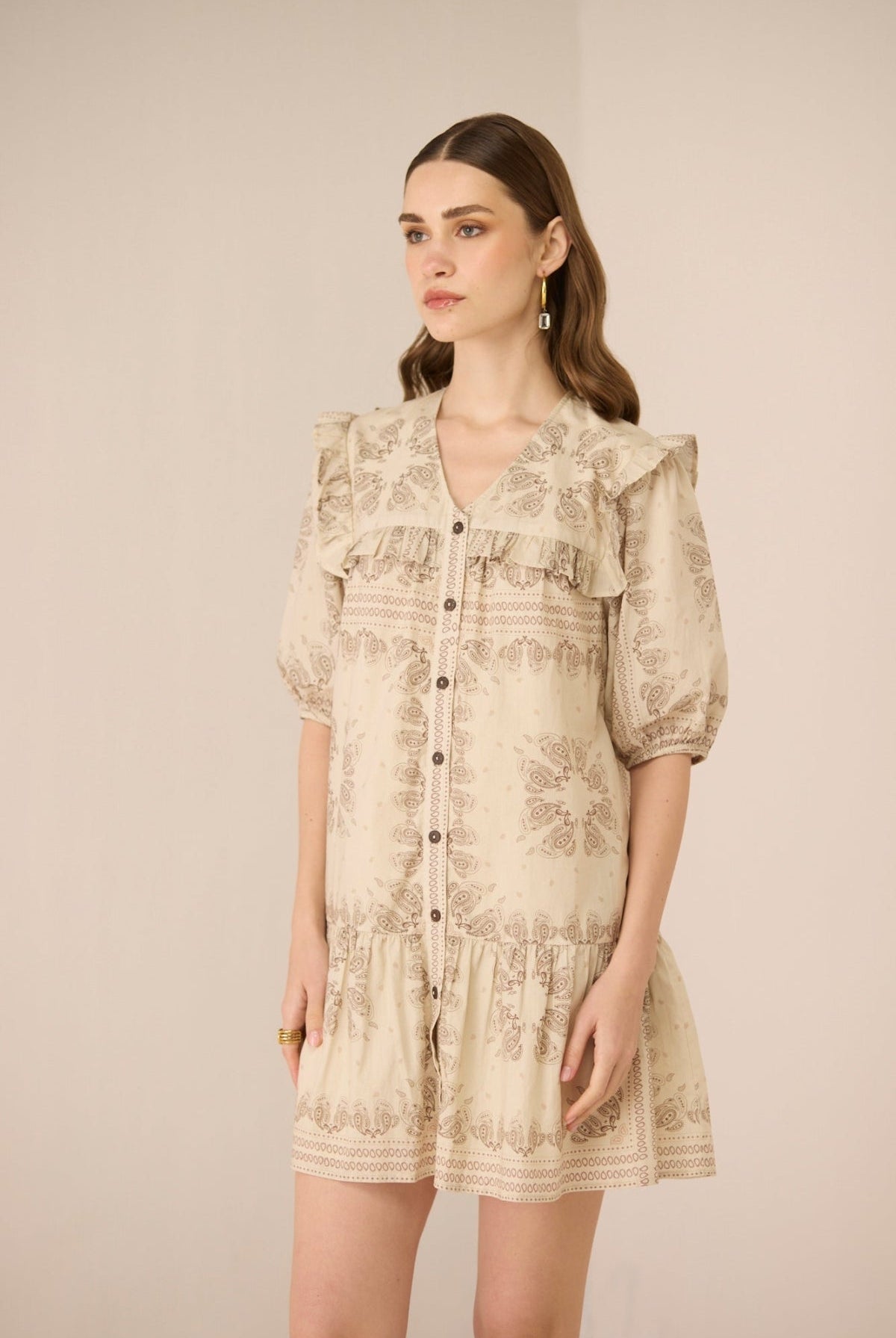 Woman wearing a beige floral dress against a plain background Calling June