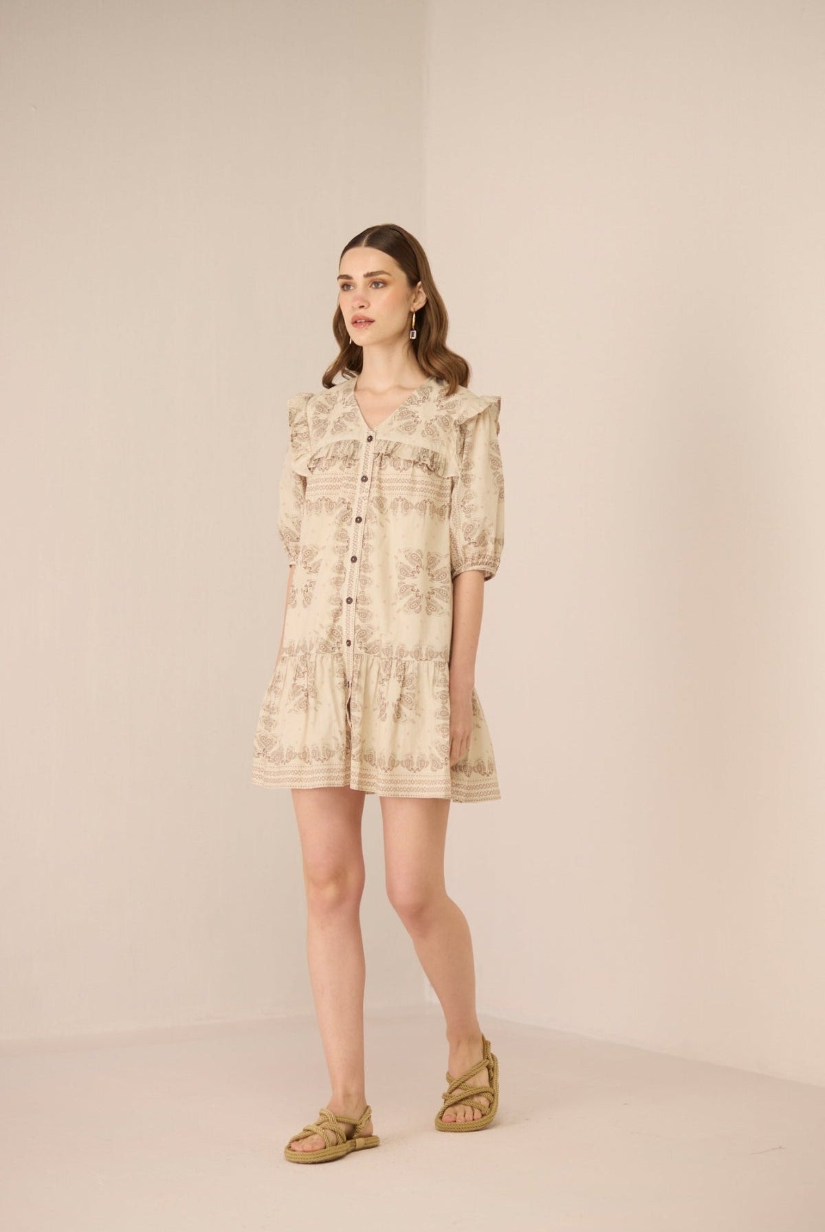 Woman wearing a beige floral dress against a plain background Calling June