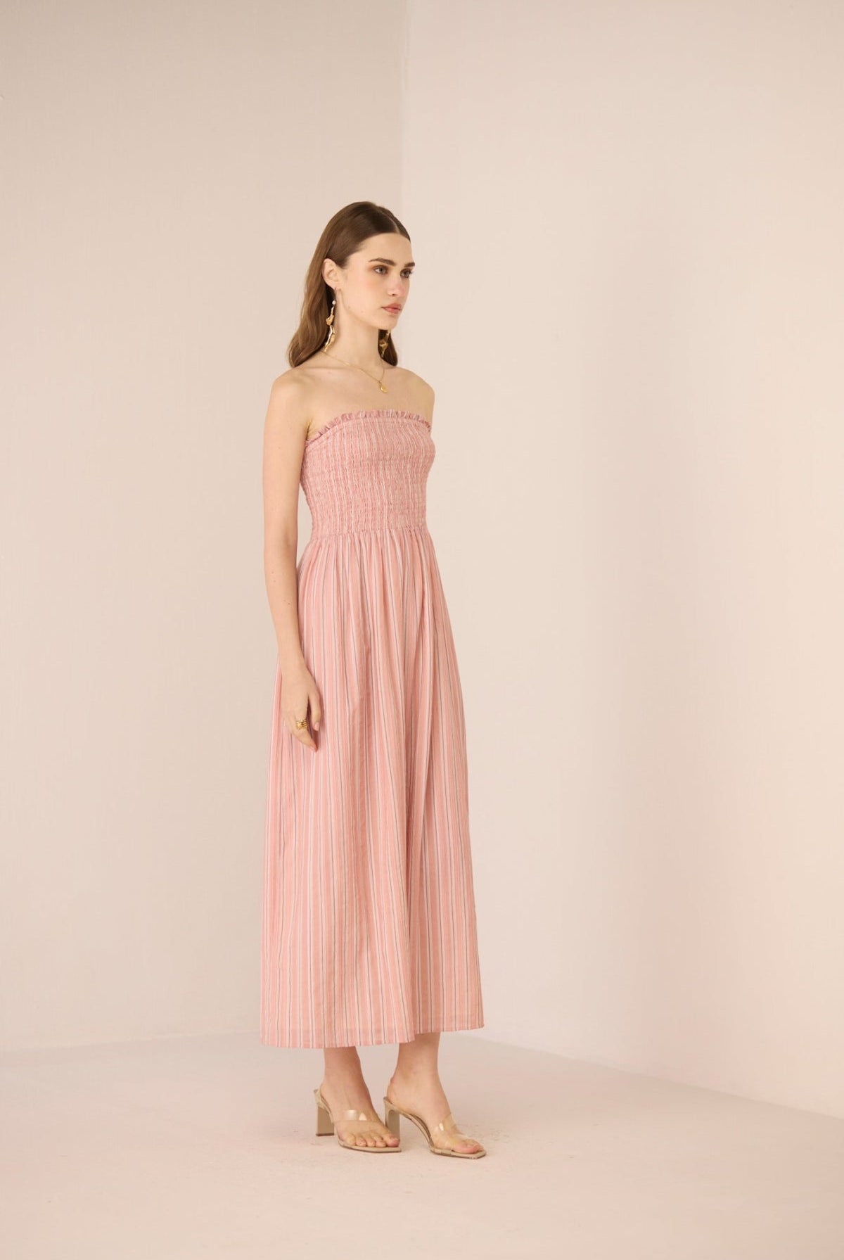 Woman wearing a pink strapless dress against a plain background Calling June