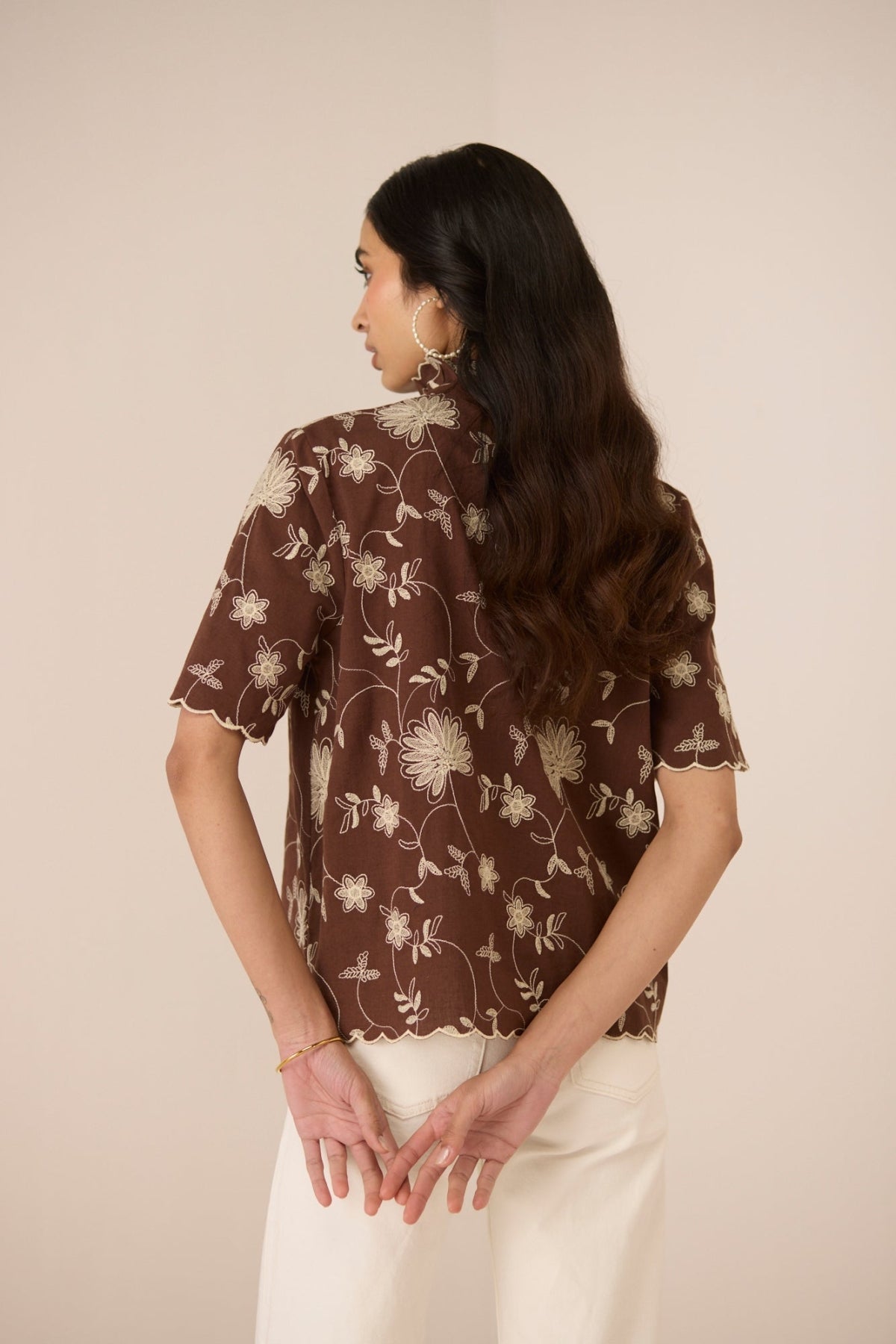 Woman wearing a brown floral blouse against a beige background Calling June