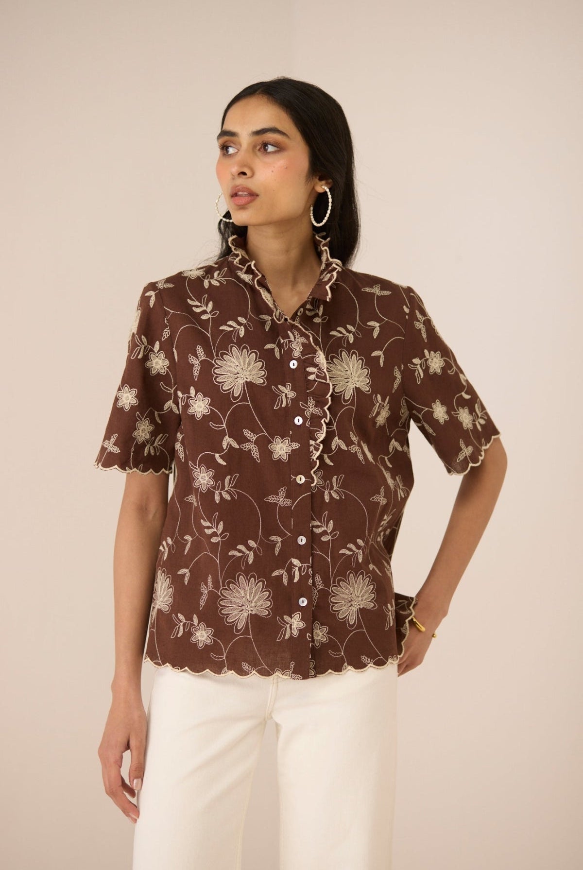 Woman wearing a brown floral blouse against a beige background Calling June