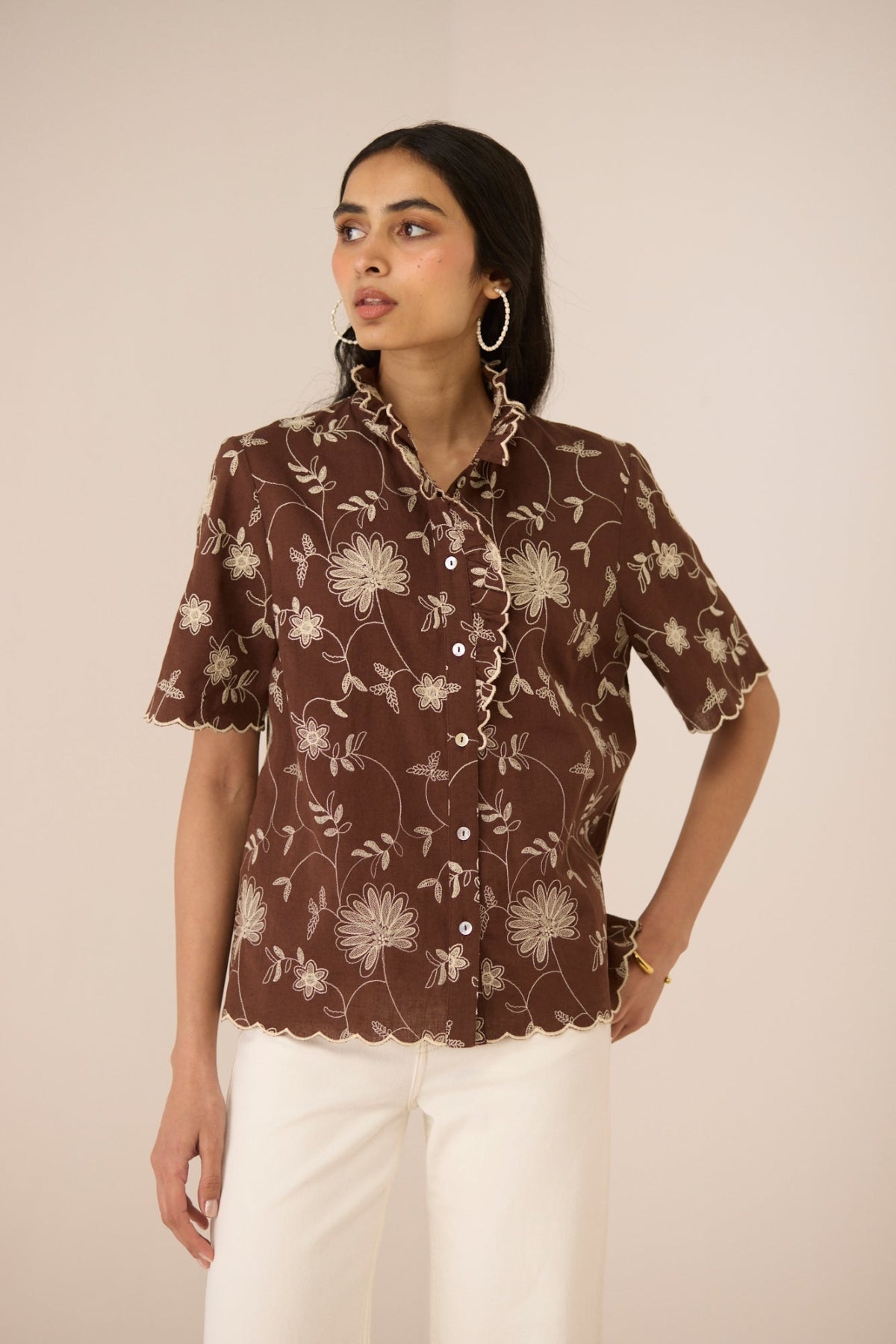 Woman wearing a brown floral blouse against a beige background Calling June