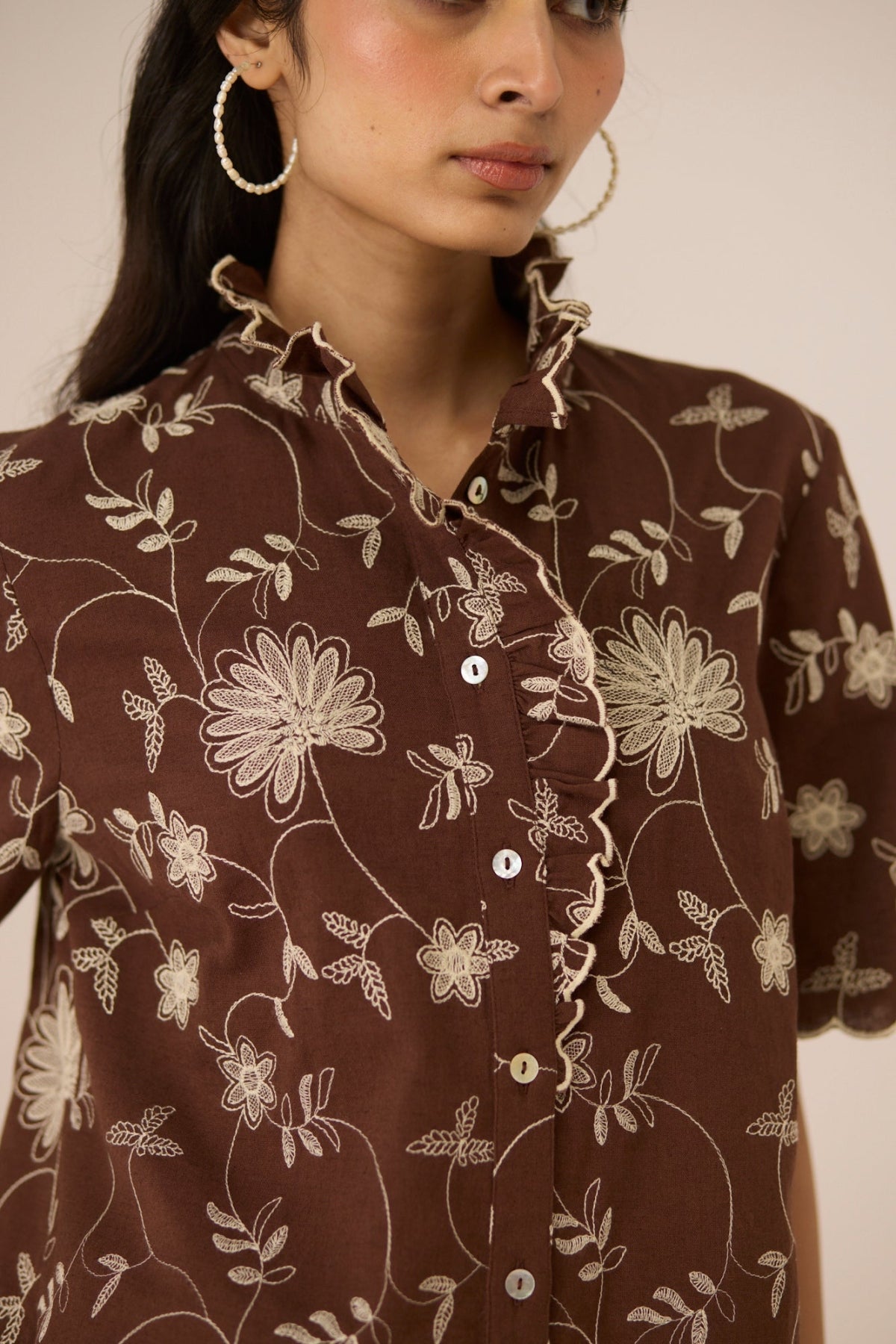 Woman wearing a brown floral patterned shirt against a neutral background Calling June