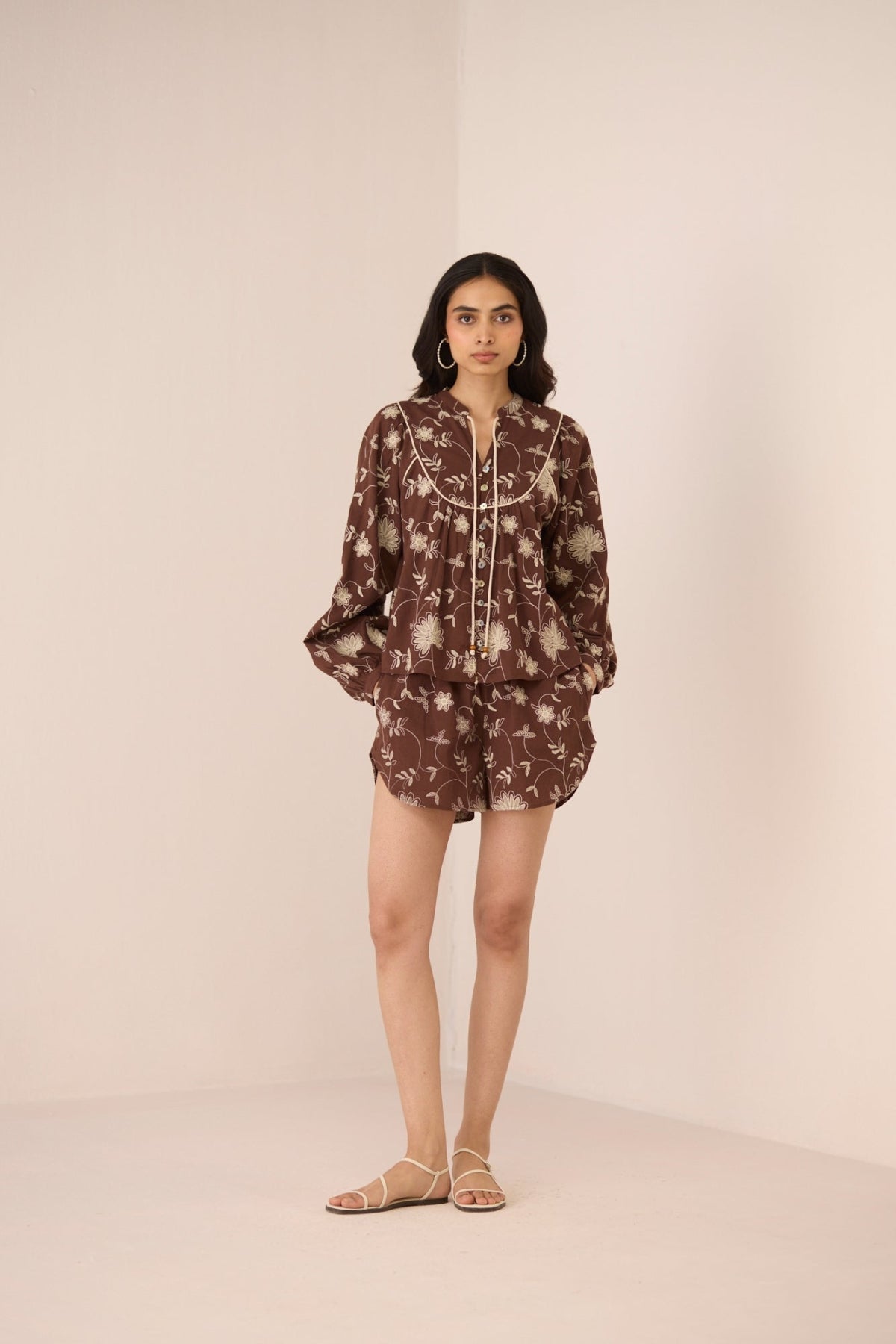 Woman wearing a brown floral dress against a plain background Calling June