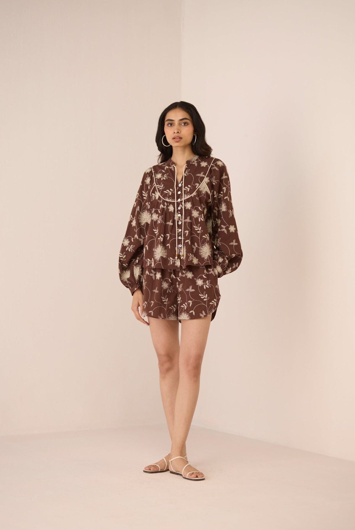 Woman wearing a brown floral dress against a beige background Calling June