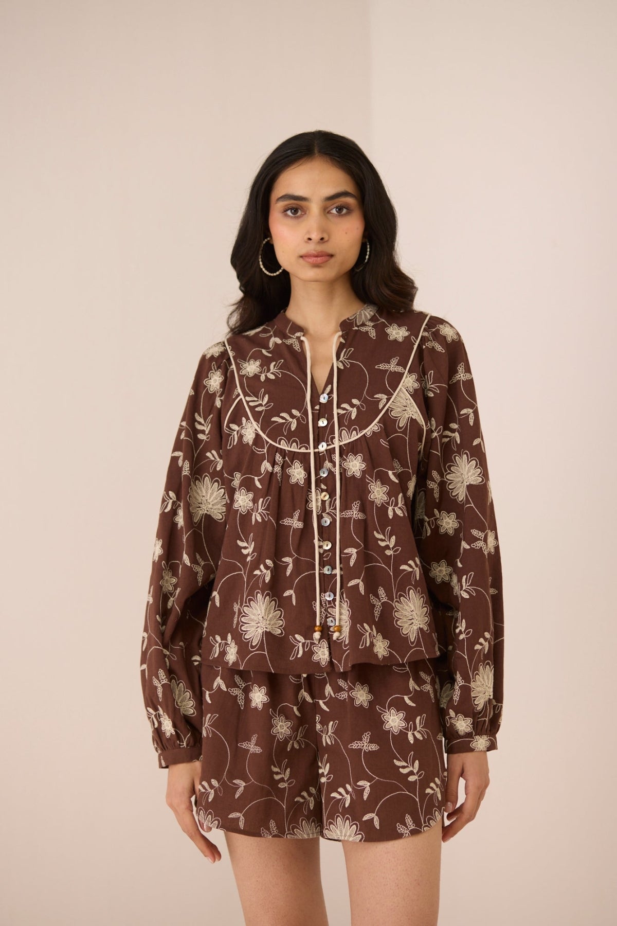 Woman wearing a brown floral patterned outfit on a beige background Calling June