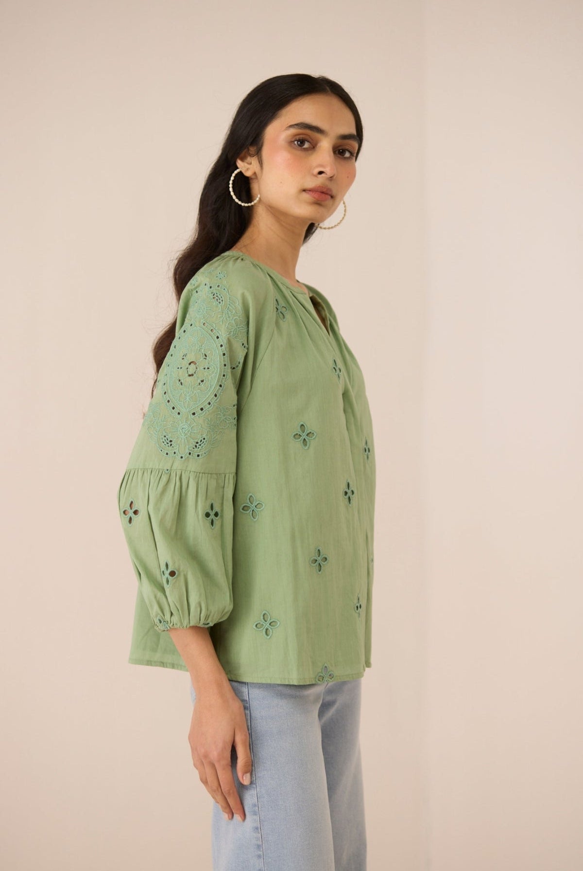 Woman wearing a green embroidered blouse against a beige background Calling June