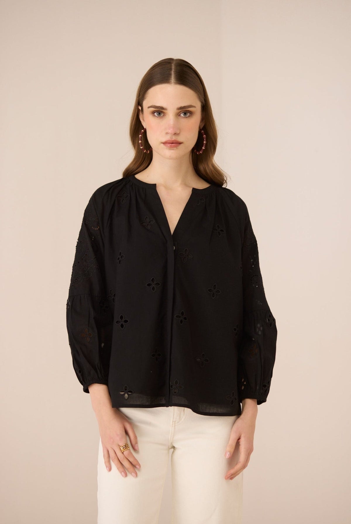 Woman wearing a black blouse with floral details on a beige background Calling June