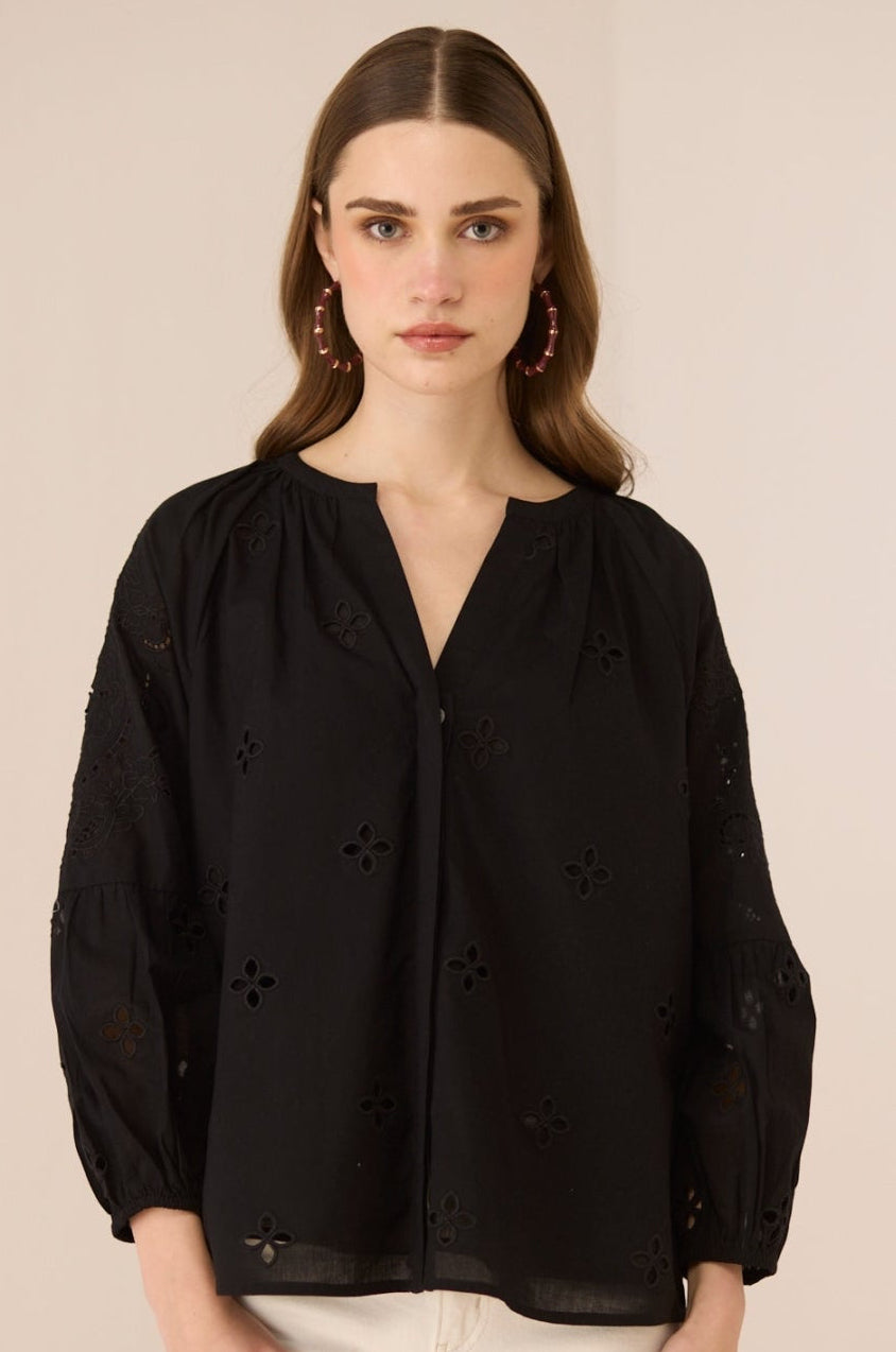 Woman wearing a black blouse with floral details on a beige background Calling June