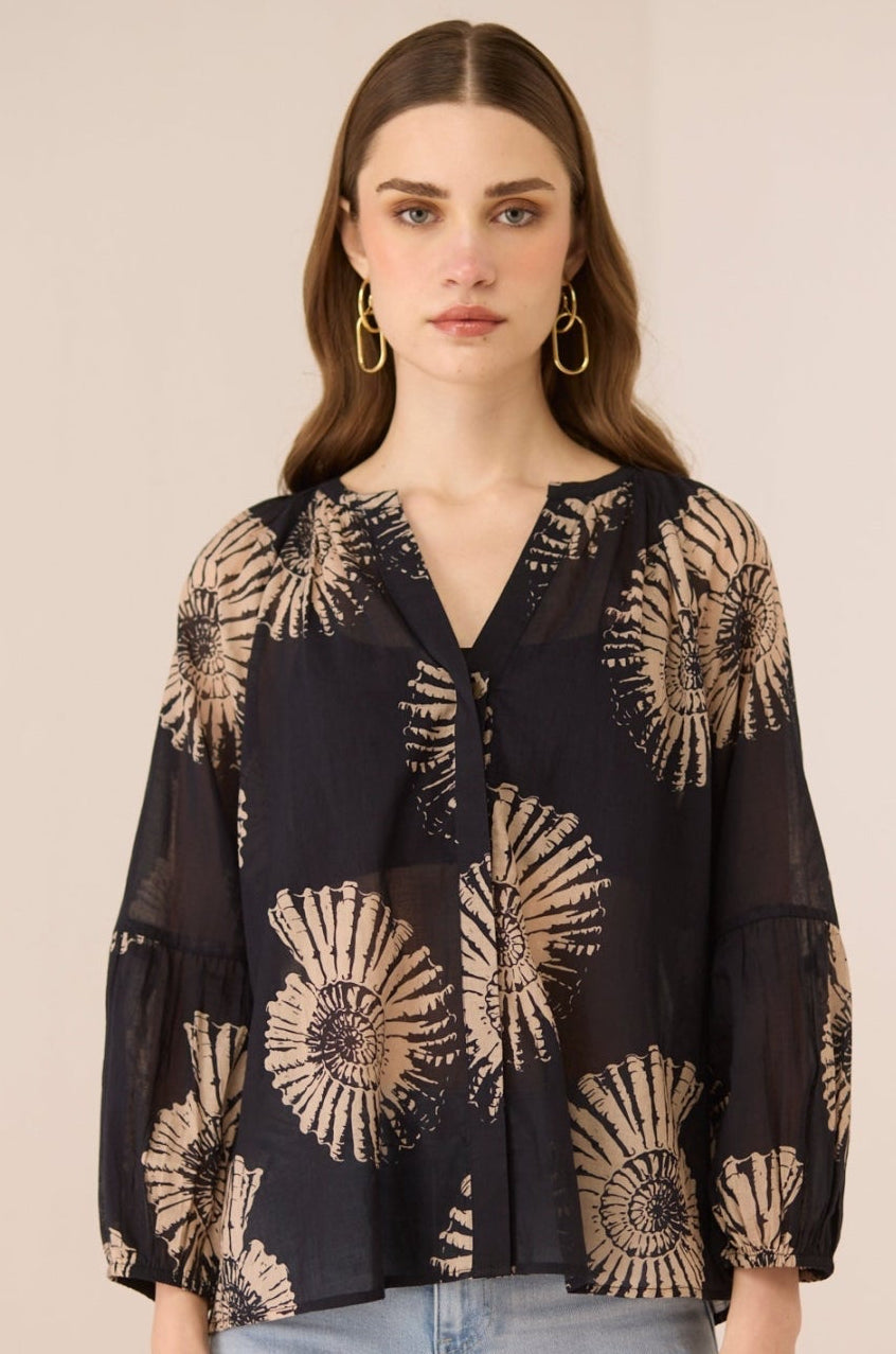 Woman wearing a black blouse with gold floral patterns on a beige background Calling June