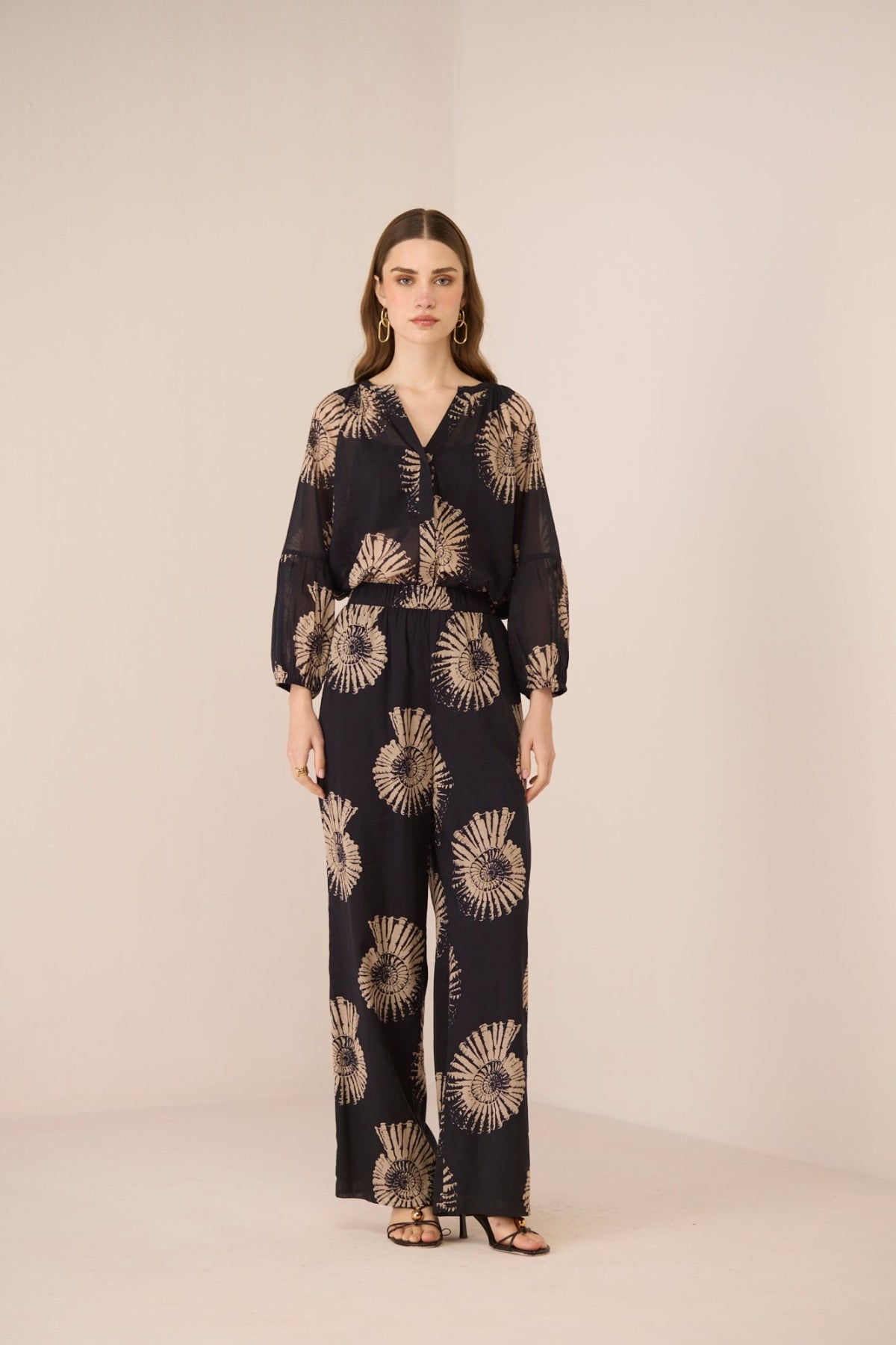 Woman wearing a black floral patterned outfit on a beige background Calling June