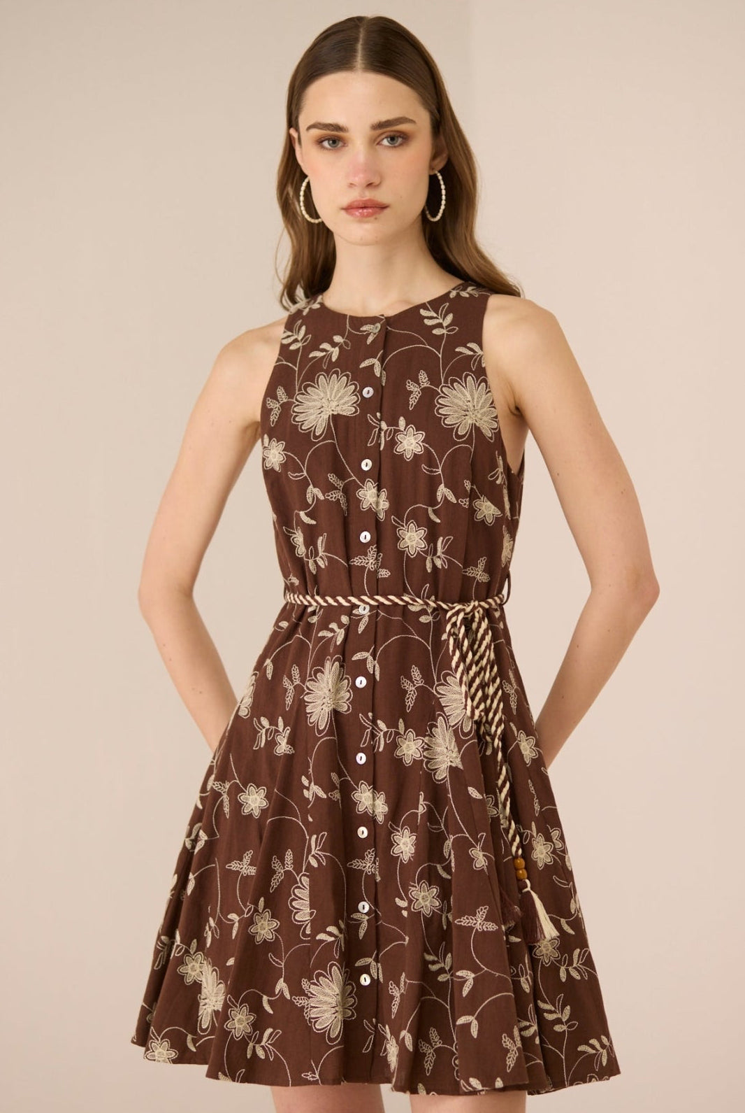 Woman wearing a brown floral dress against a beige background Calling June
