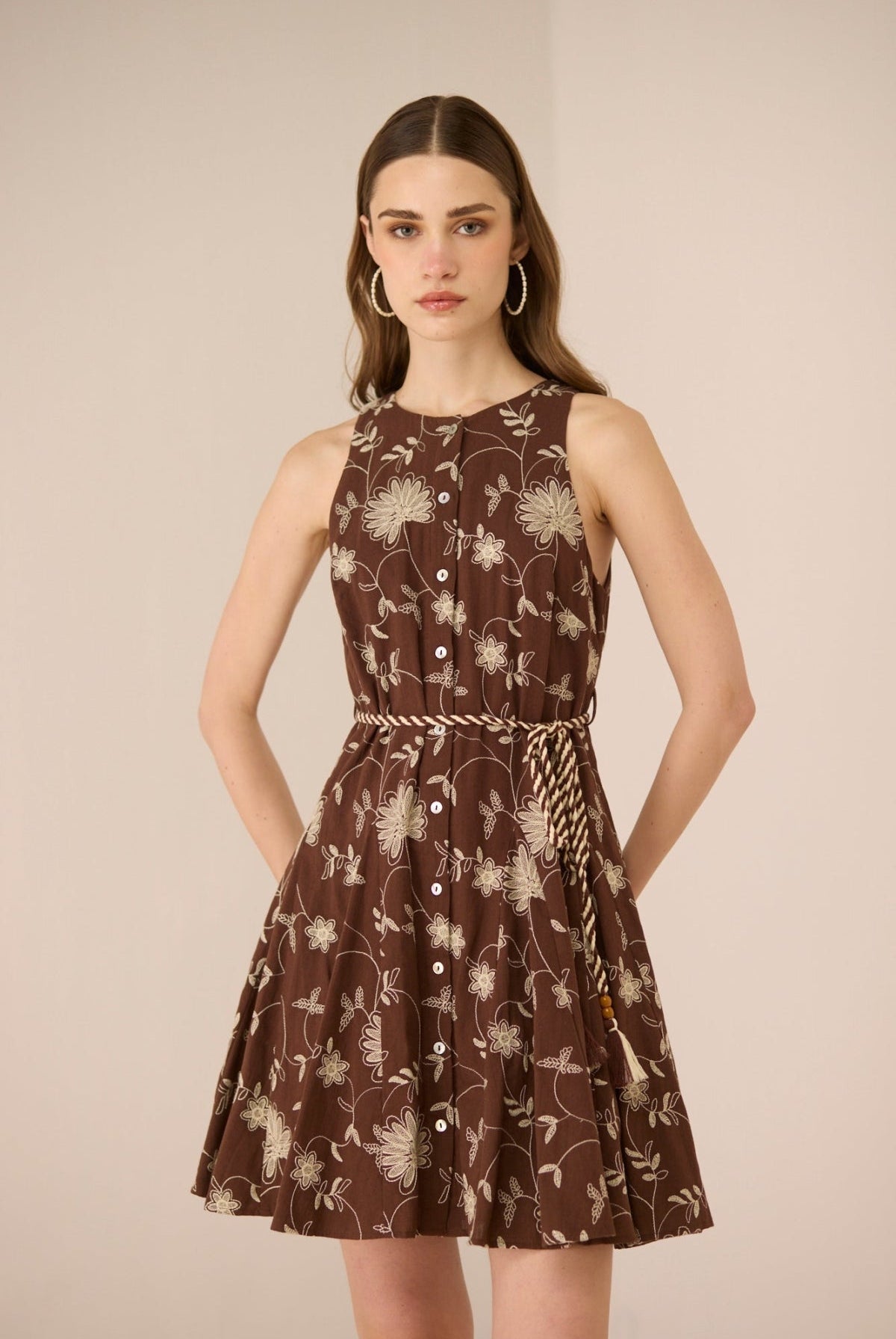 Woman wearing a brown floral dress against a beige background Calling June