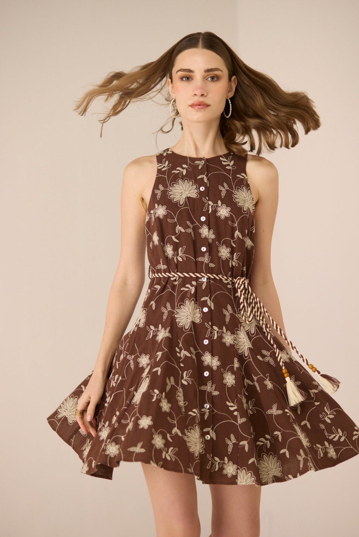 Woman wearing a brown floral dress against a beige background Calling June