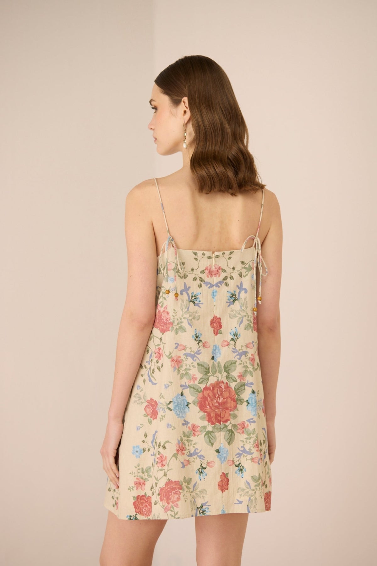Woman wearing a floral dress with a beige background Calling June