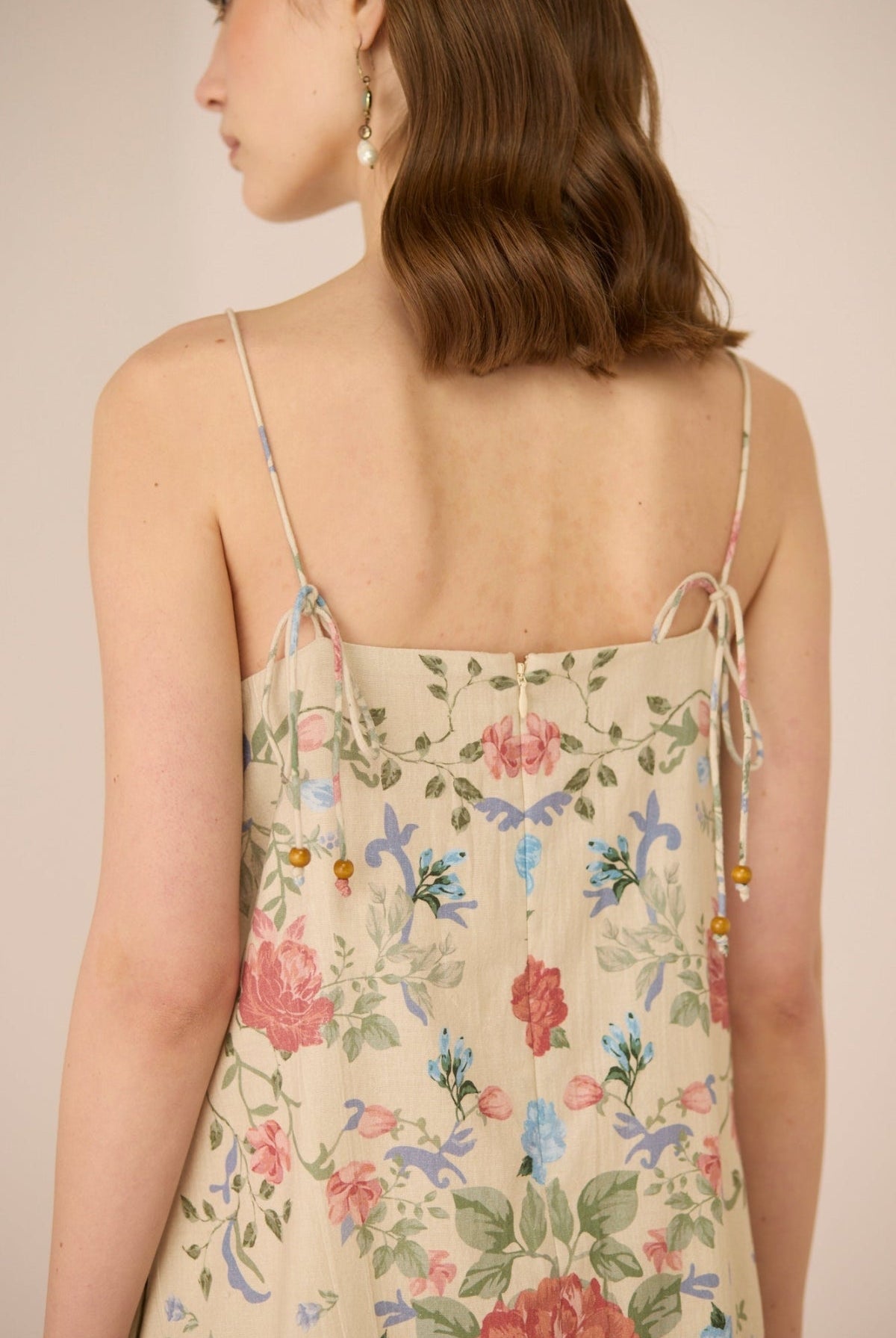 Woman wearing a floral dress with thin straps on a beige background Calling June