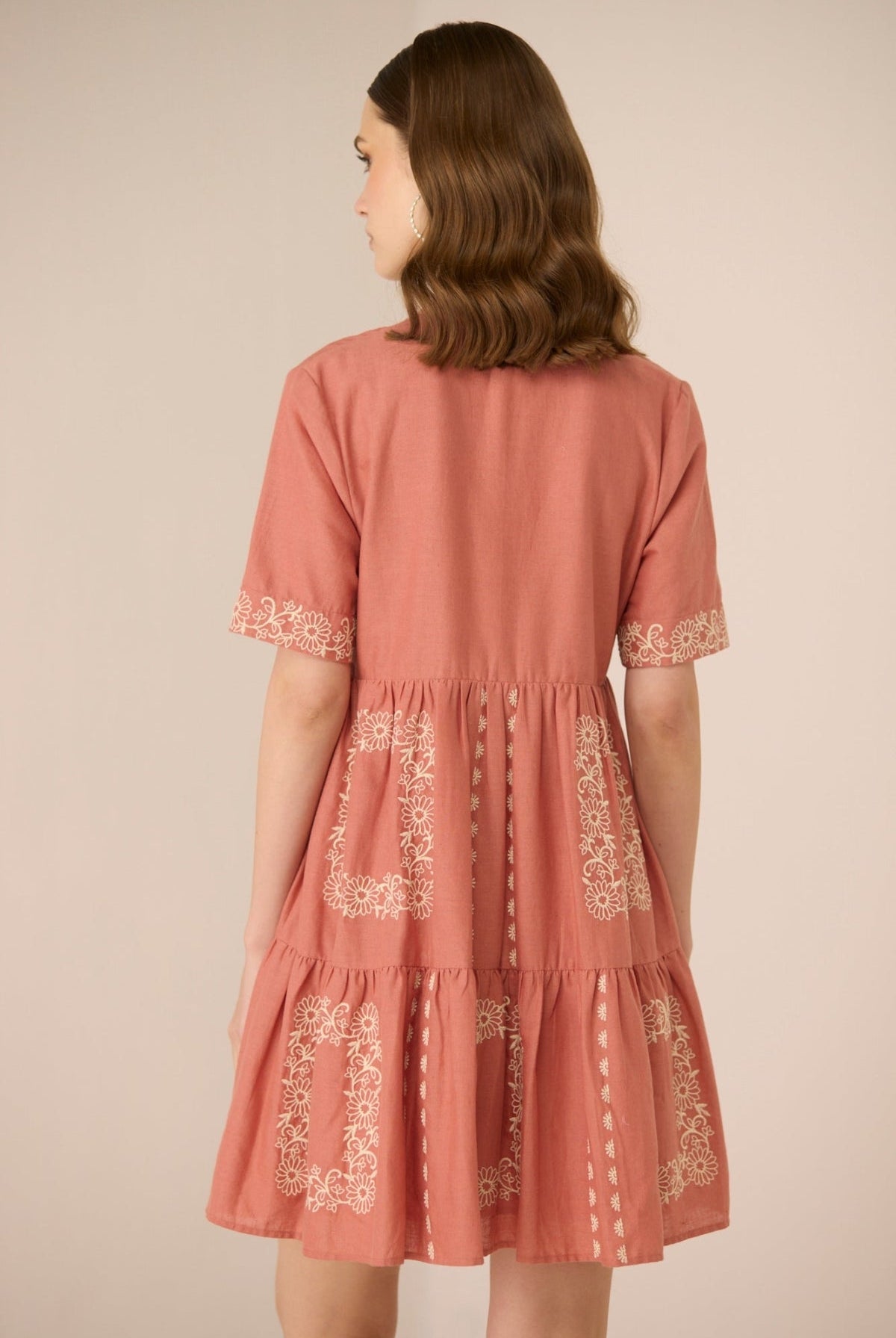 Woman wearing a pink dress with lace details on a beige background Calling June