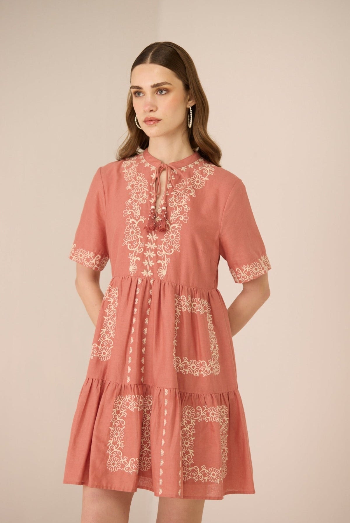 Woman wearing a pink dress with lace details on a beige background Calling June