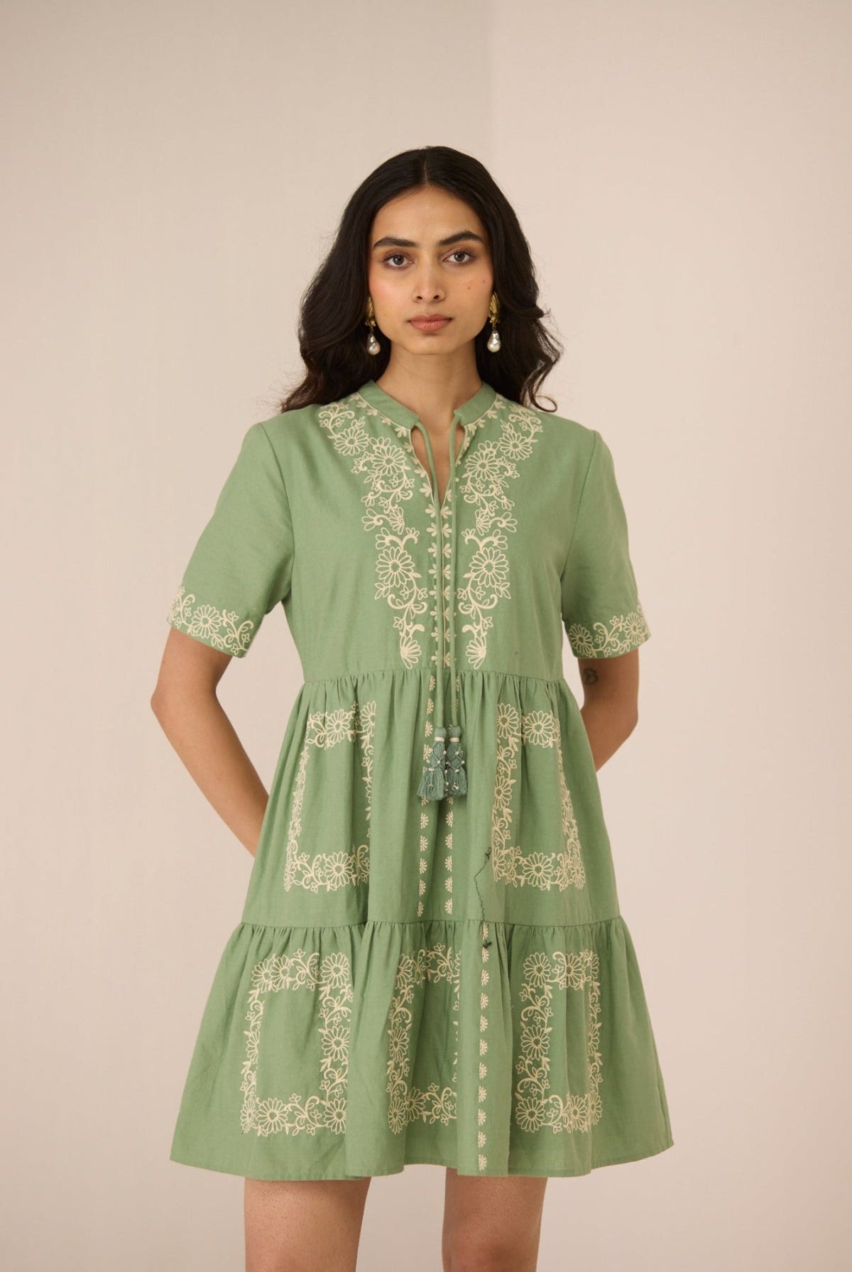 Woman wearing a green embroidered dress against a plain background Calling June