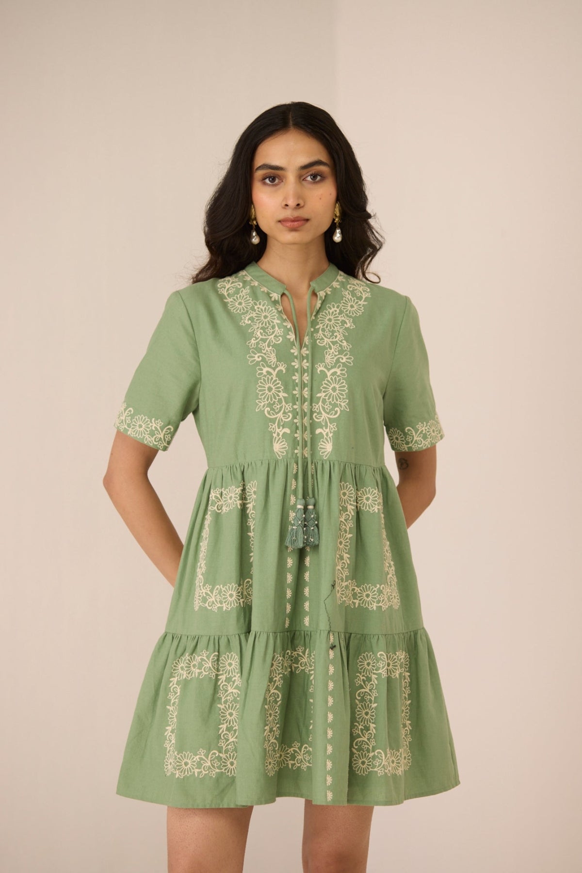 Woman wearing a green embroidered dress against a plain background Calling June