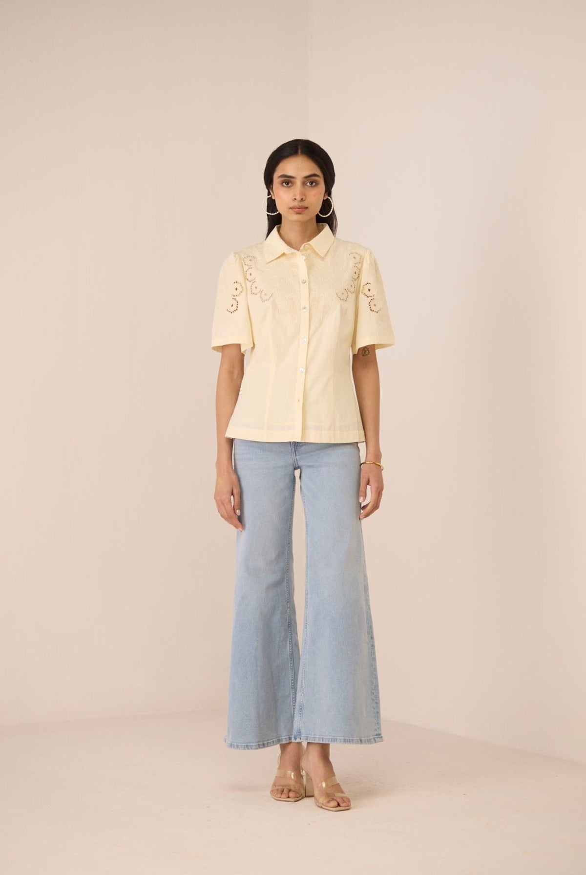 Woman wearing a light yellow blouse with short sleeves and light blue jeans on a beige background Calling June