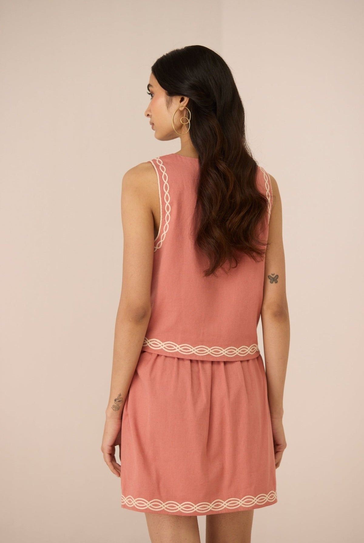 Woman wearing a pink dress with lace trim on a beige background Calling June