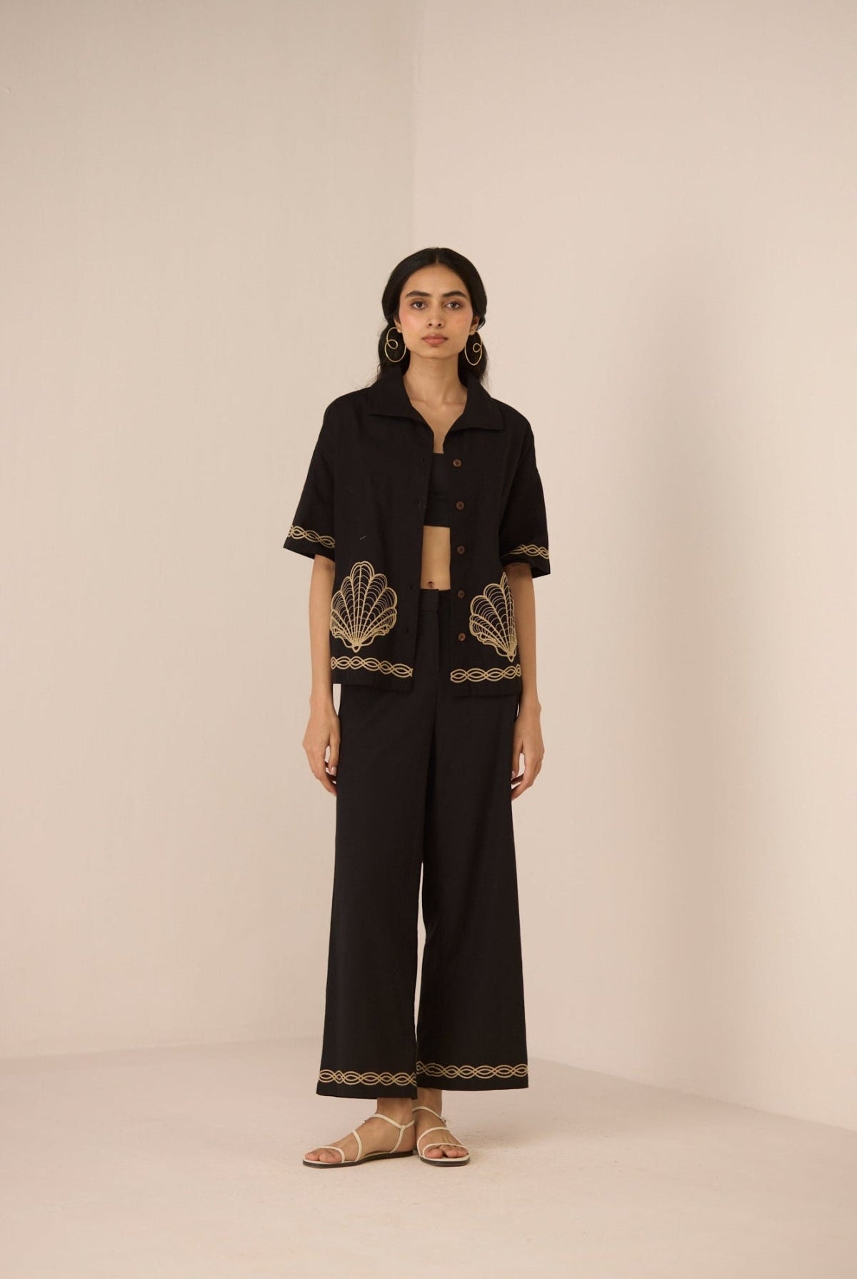 Woman wearing a black outfit with gold embroidery on a beige background Calling June