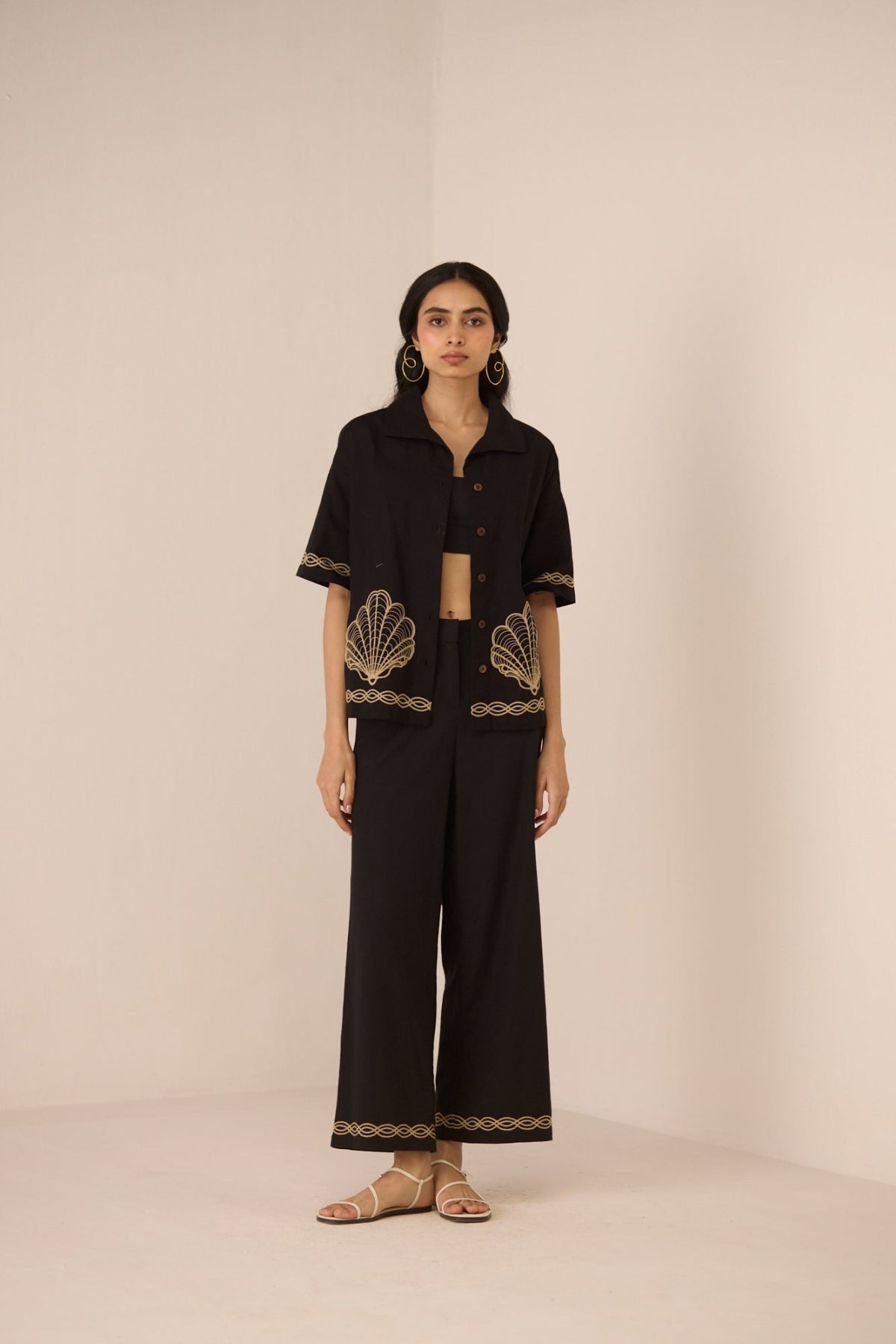 Woman wearing a black outfit with gold embroidery on a beige background Calling June