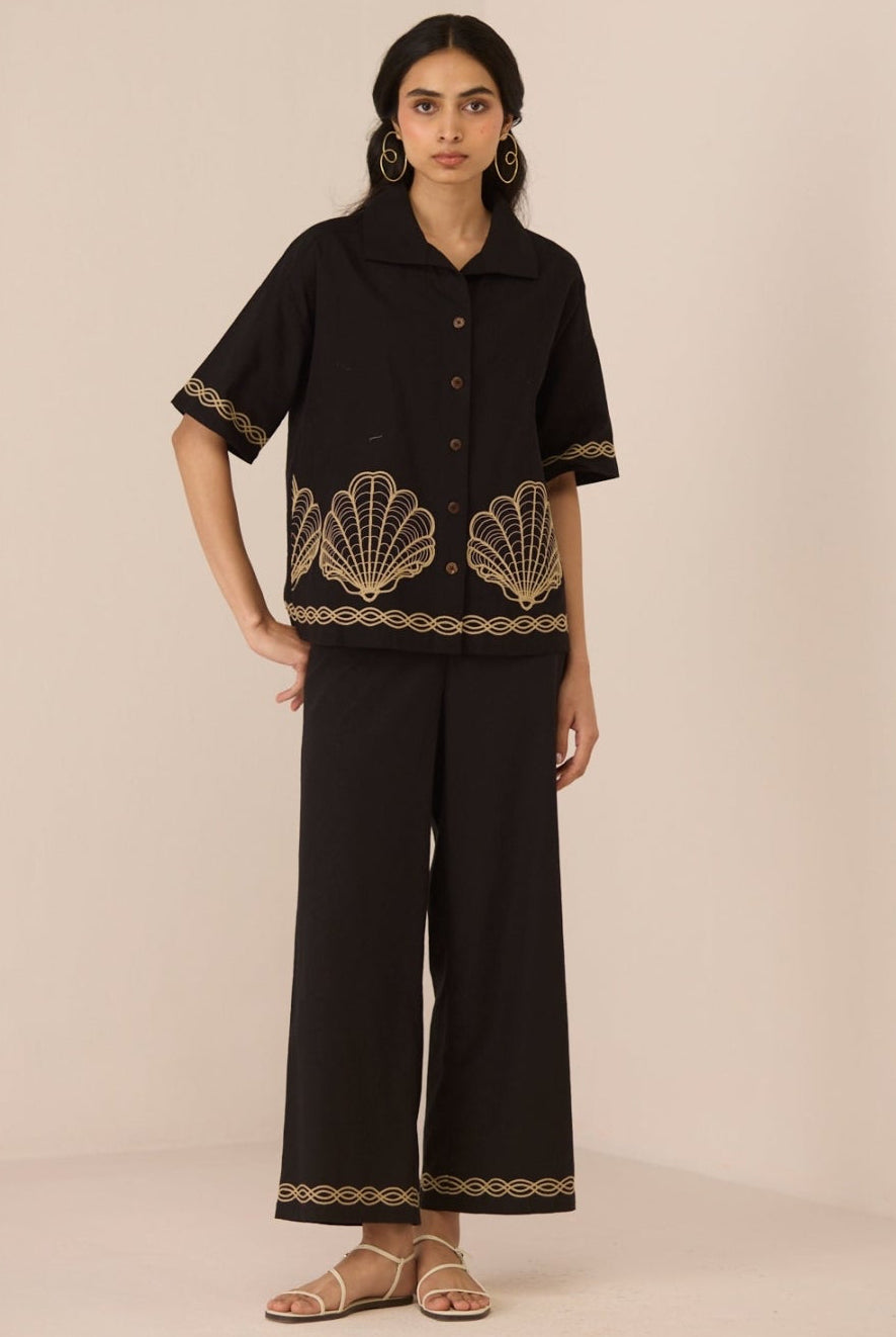 Woman wearing a black outfit with shell patterns on a beige background Calling June