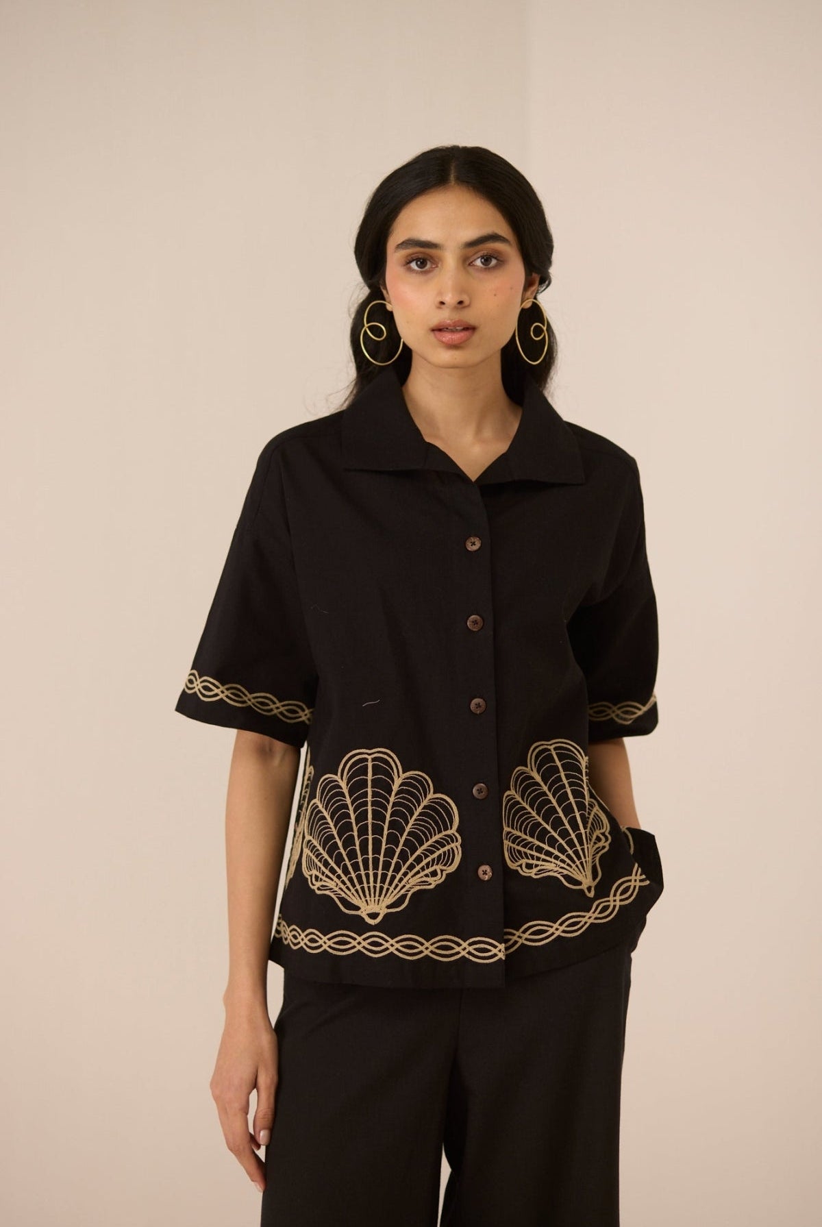 Woman wearing a black top with gold embroidery on a beige background Calling June