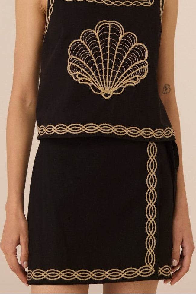 Woman wearing a black dress with gold embroidery on a beige background Calling June