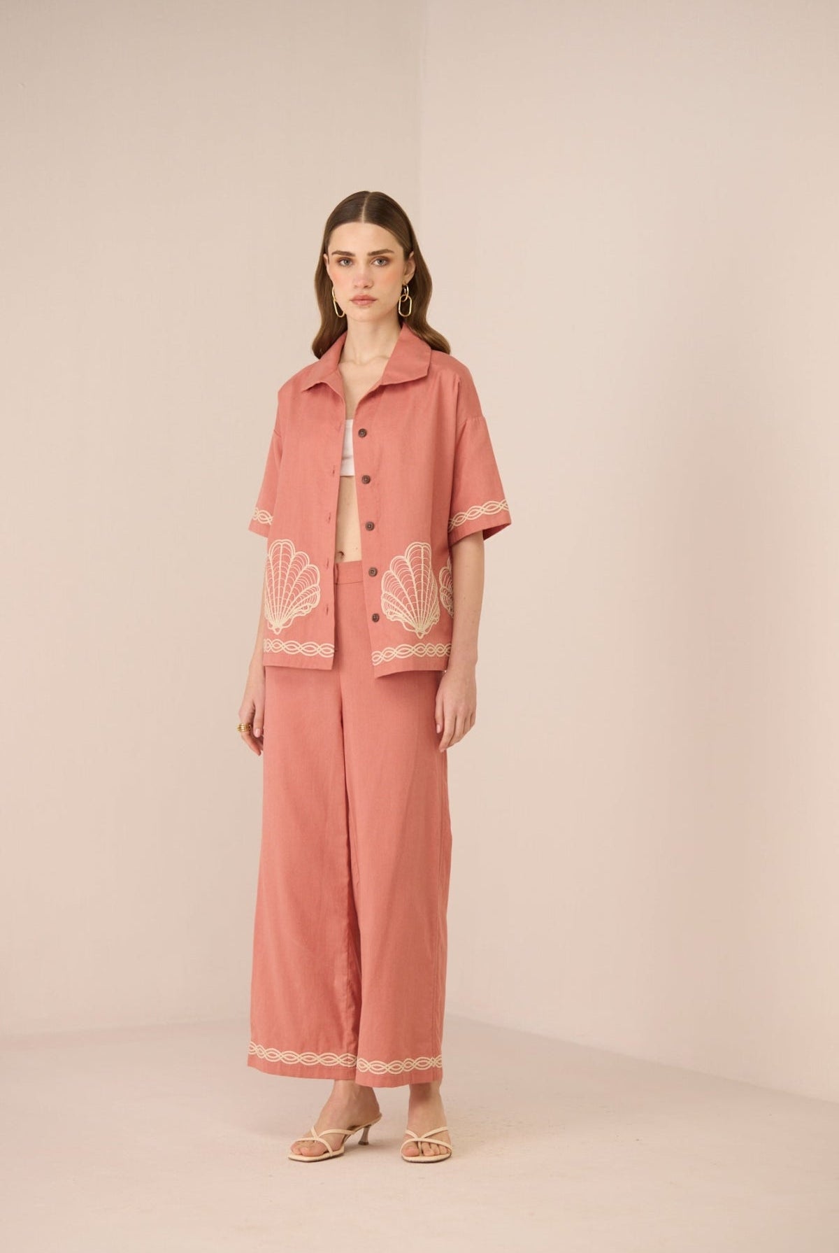 Woman wearing a coral pajama set with lace details on a beige background Calling June