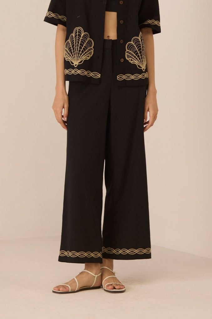 Woman wearing a black outfit with gold embroidery on a beige background Calling June