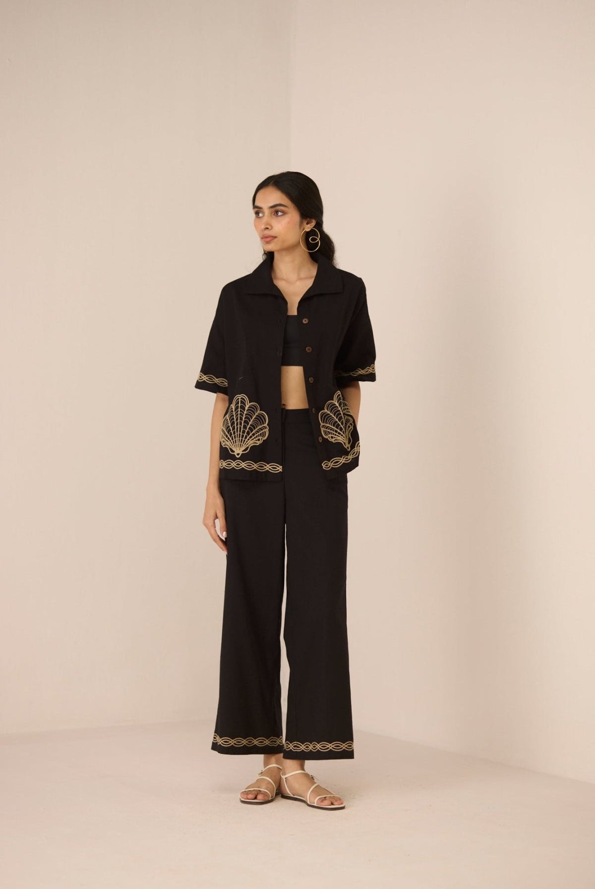 Woman wearing a black outfit with gold embroidery on a beige background Calling June