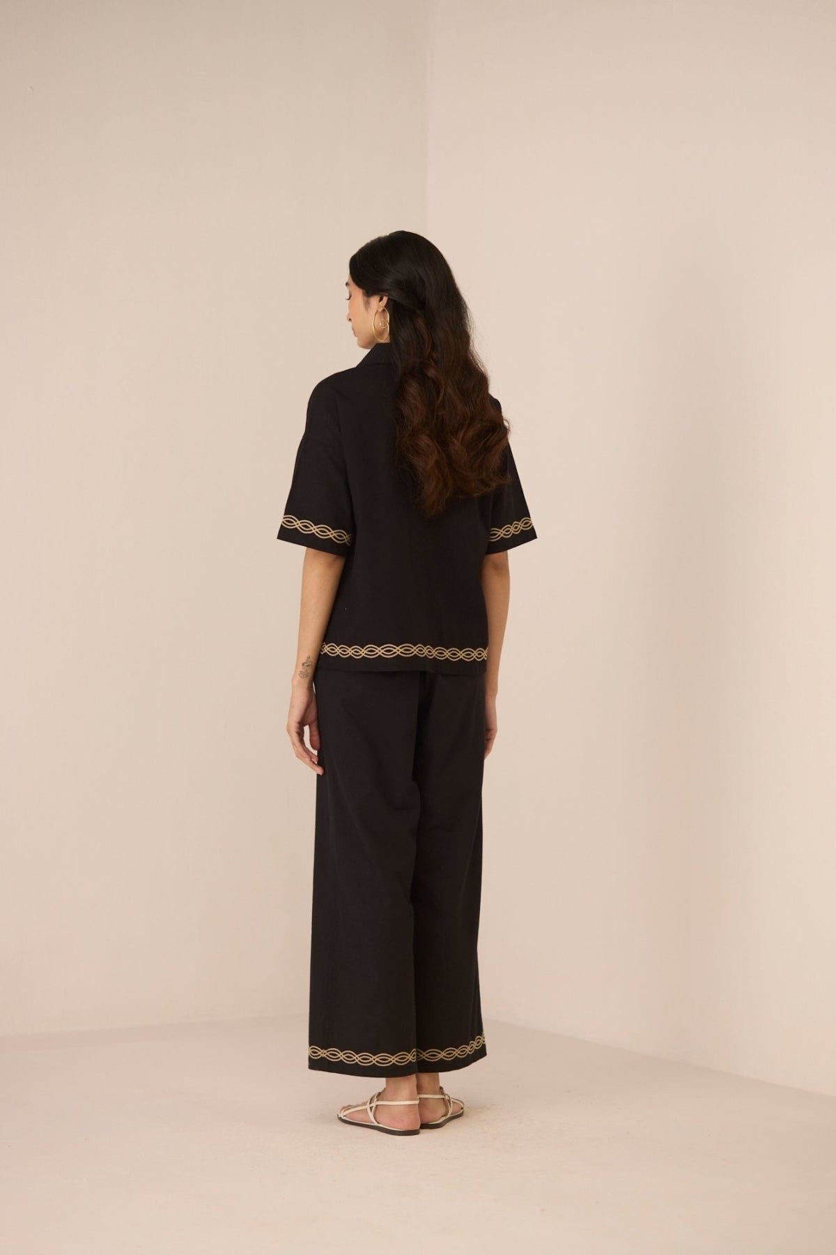 Woman wearing a black outfit with lace details on a beige background Calling June