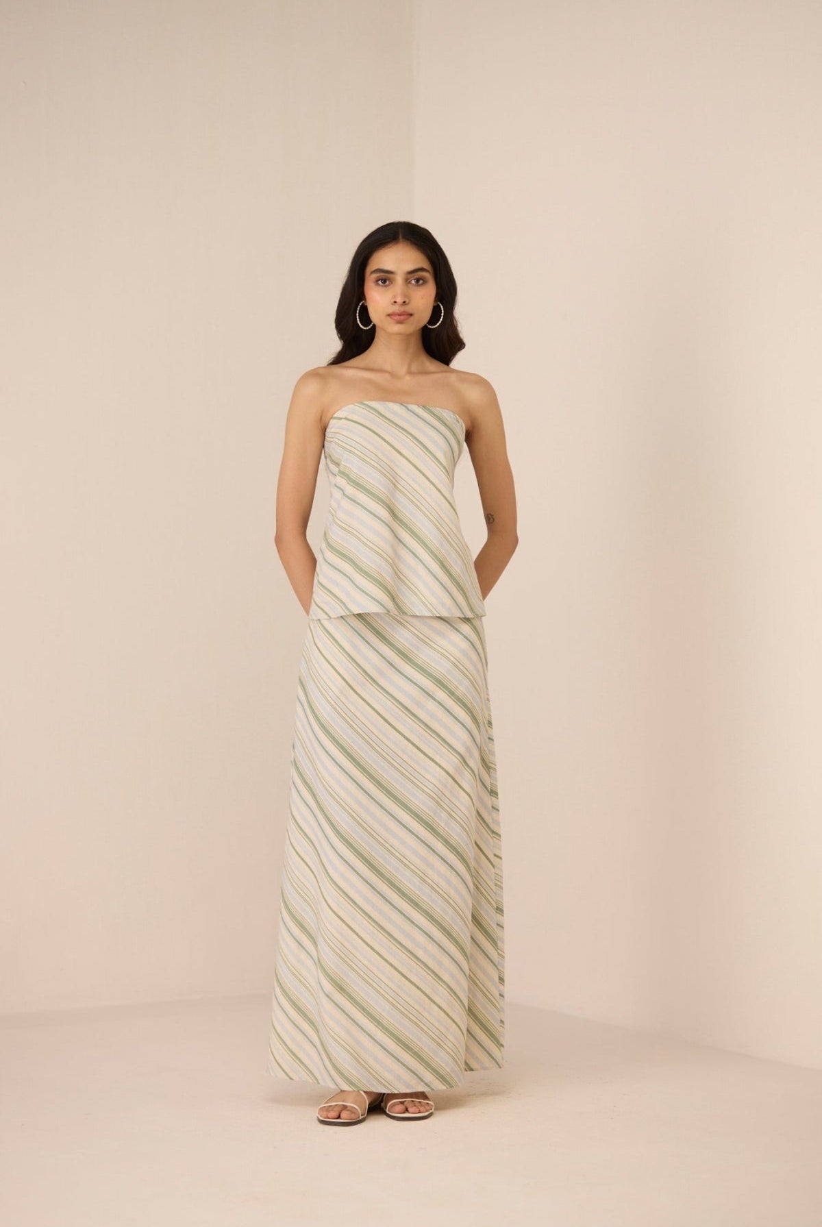 Woman wearing a strapless, long, patterned dress against a plain background Calling June