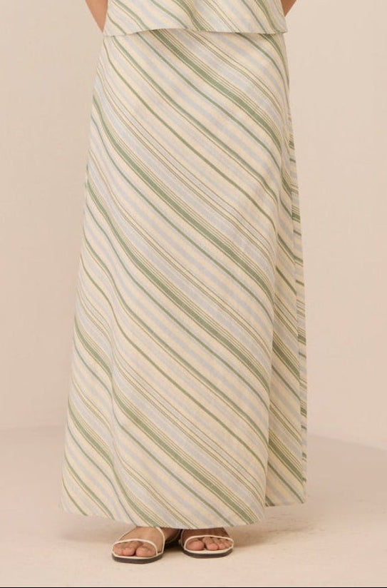 Woman wearing a strapless, long, patterned dress against a plain background Calling June